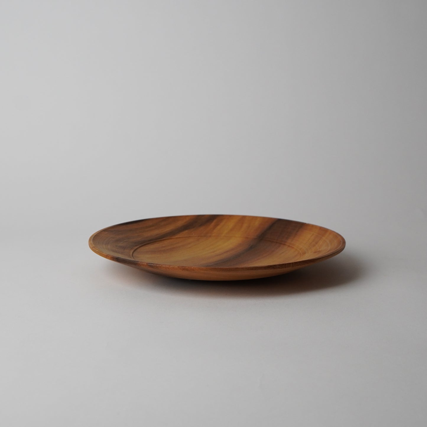 Wooden plate with a striped pattern on a light gray background