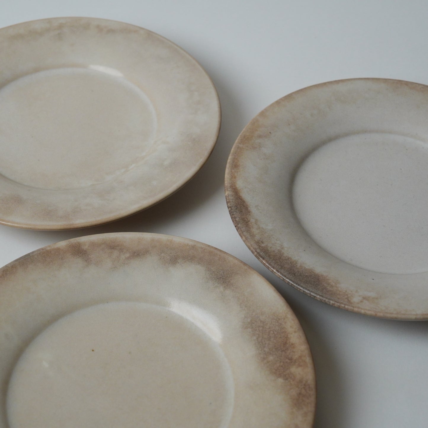 Three ceramic plates with a rustic finish on a white background