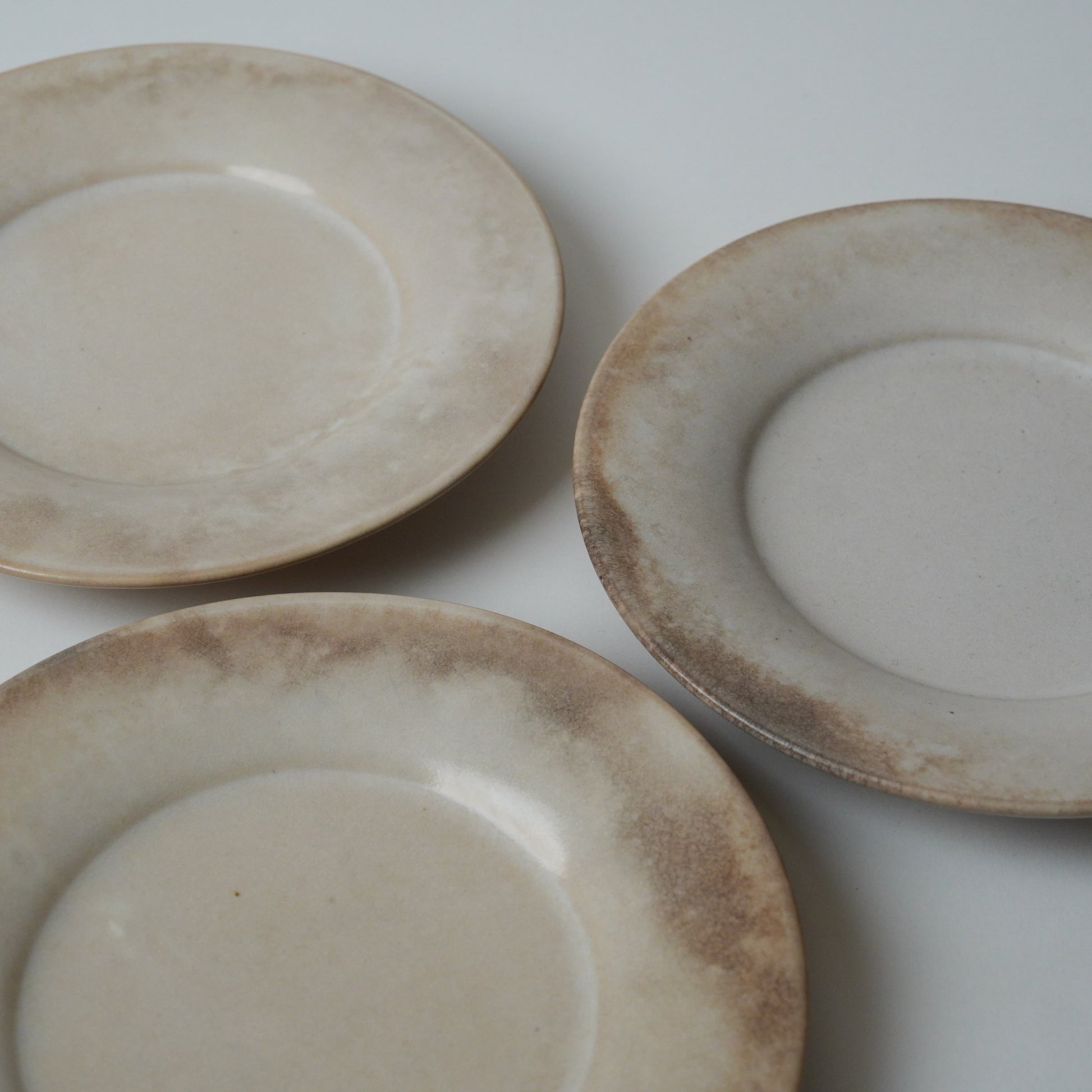 Three ceramic plates with a rustic finish on a white background