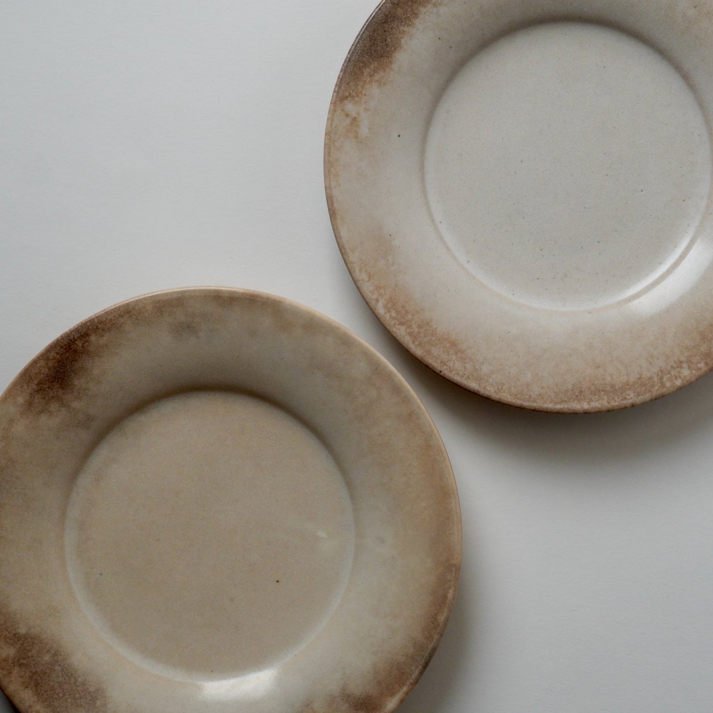 Two ceramic plates with a rustic finish on a white background