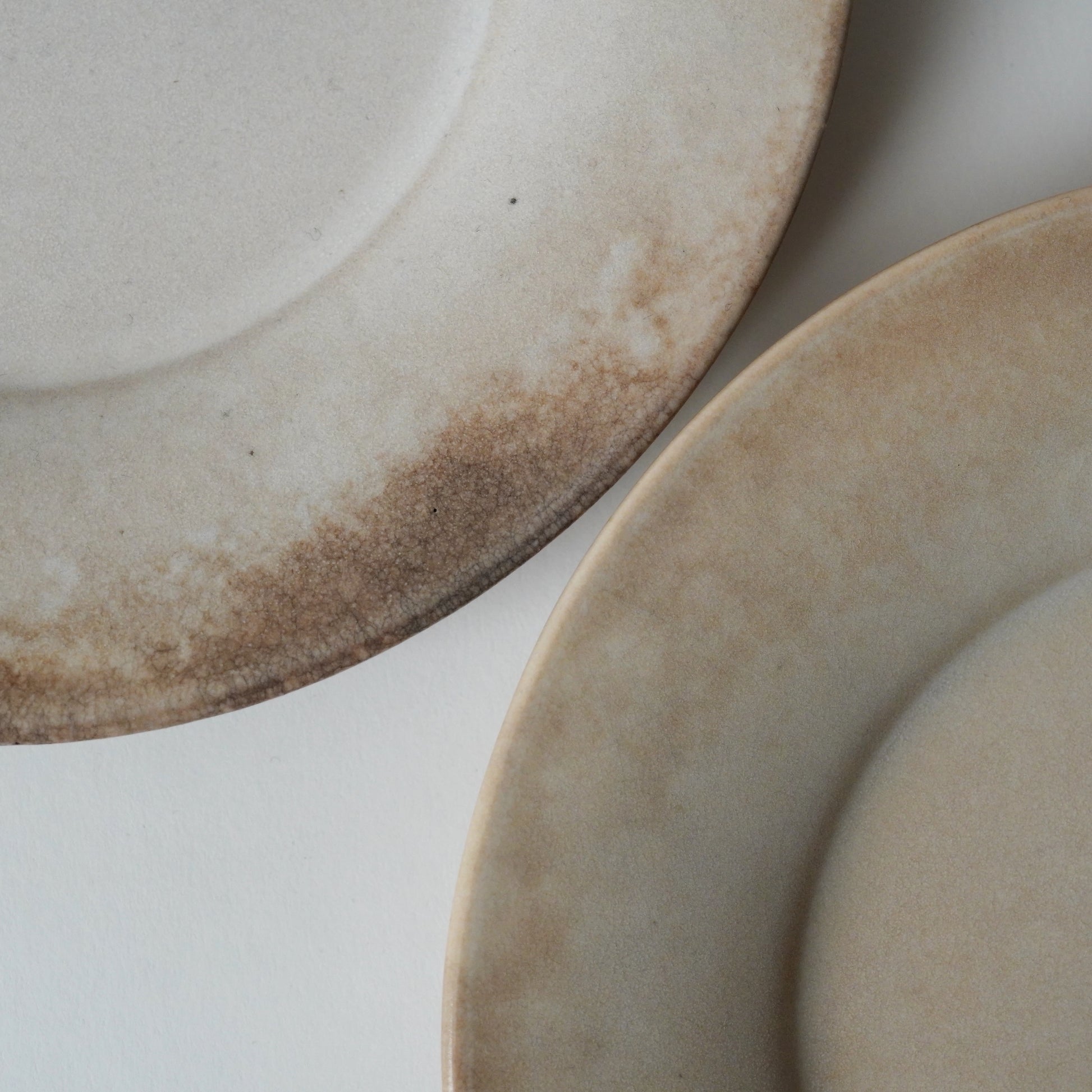 Two ceramic plates with a rustic finish on a light background