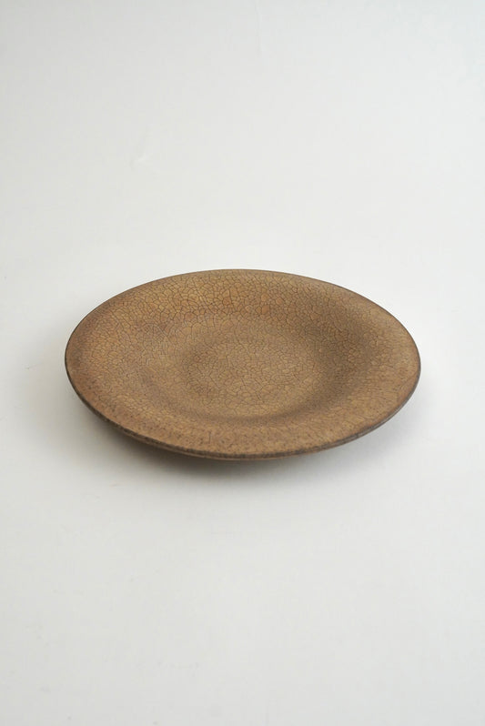 A round ceramic plate with a textured, speckled brown glaze, photographed from a top-down angle on a clean white background.