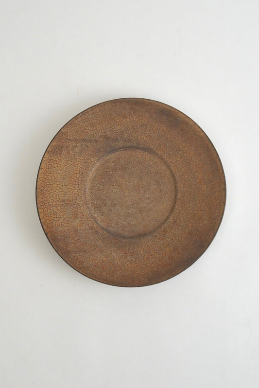 A round ceramic plate with a textured, rustic brown glaze, photographed from directly above on a clean white background.