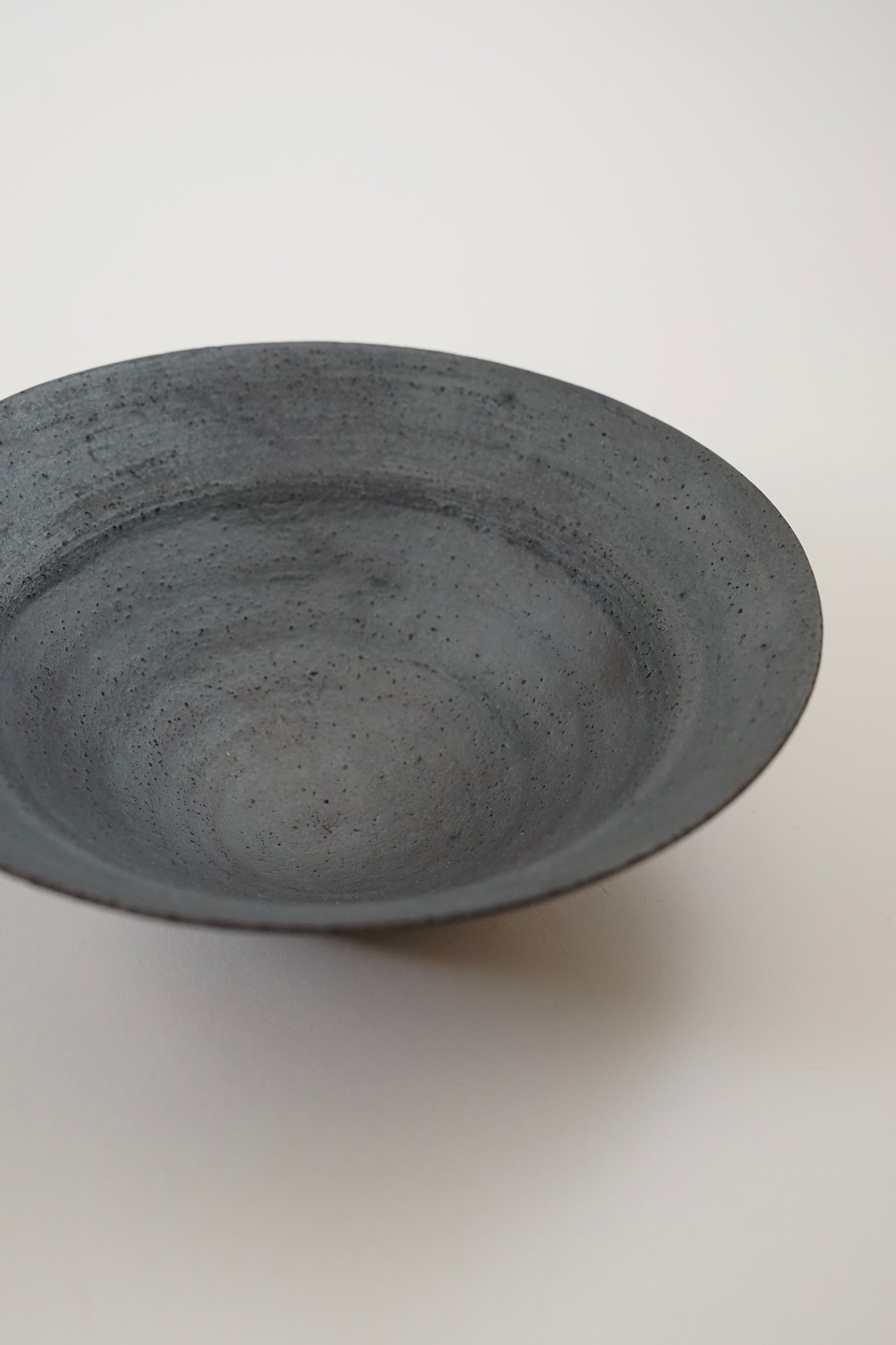 A dark gray speckled ceramic bowl photographed from a high angle on a plain off-white background.