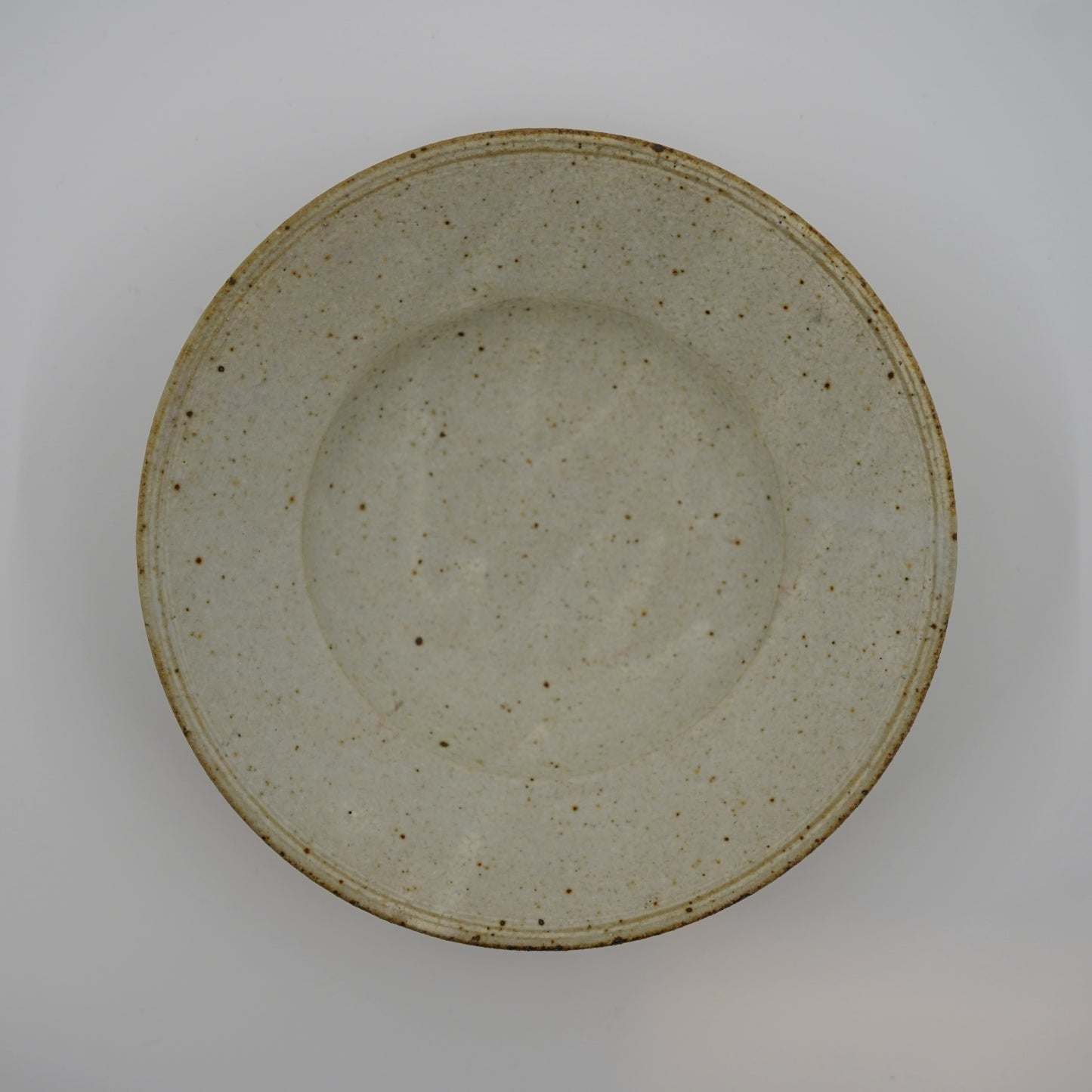 Speckled ceramic plate on a plain background