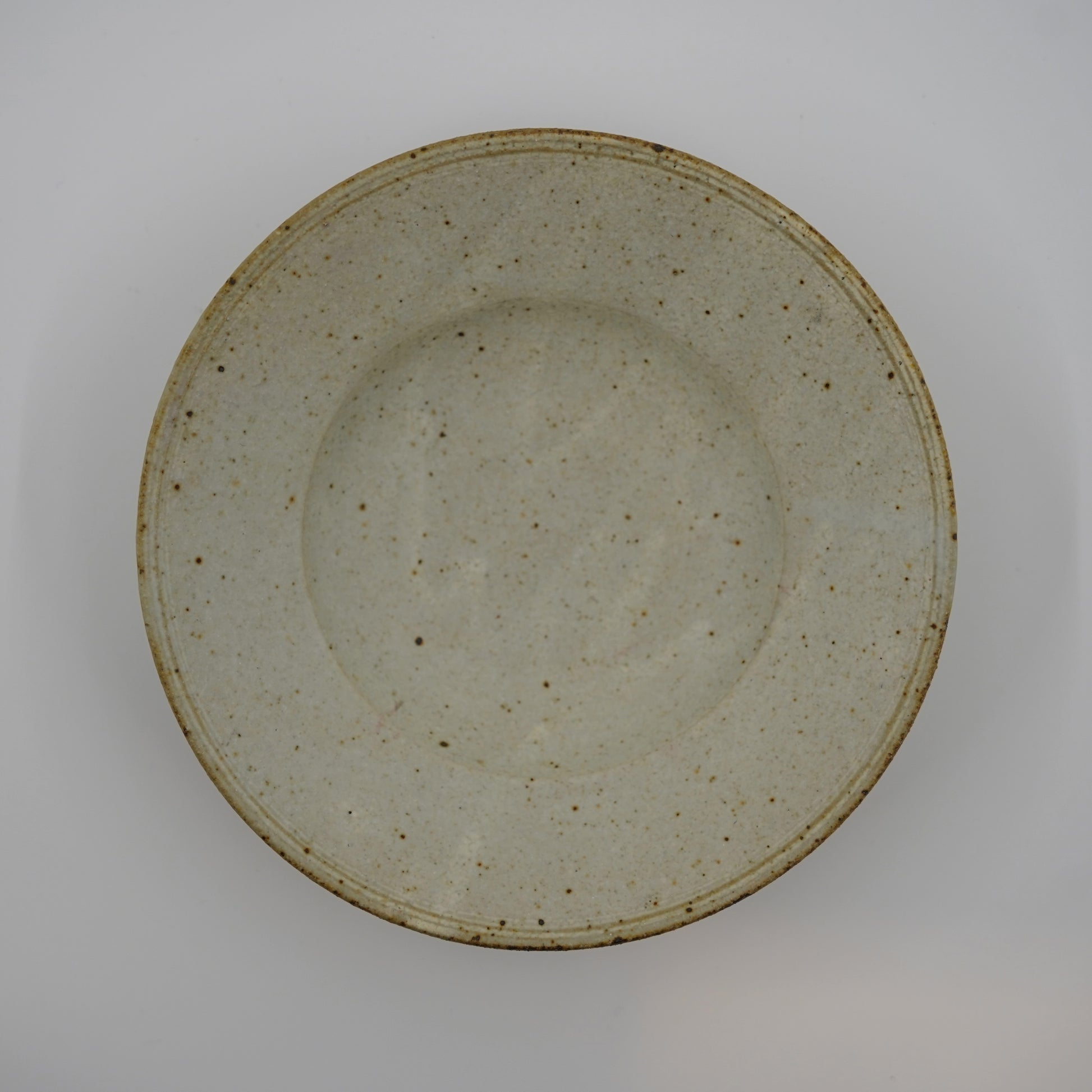 Speckled ceramic plate on a plain background