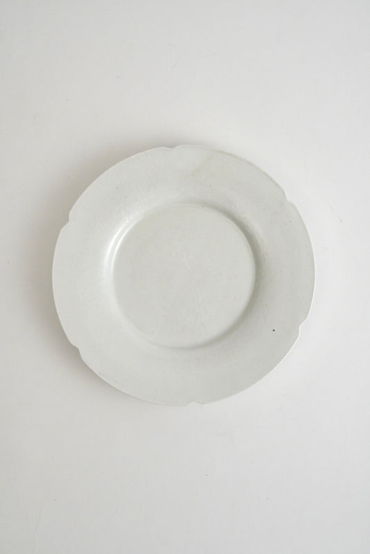 A white ceramic plate with a scalloped rim, photographed from directly above on a plain white background.