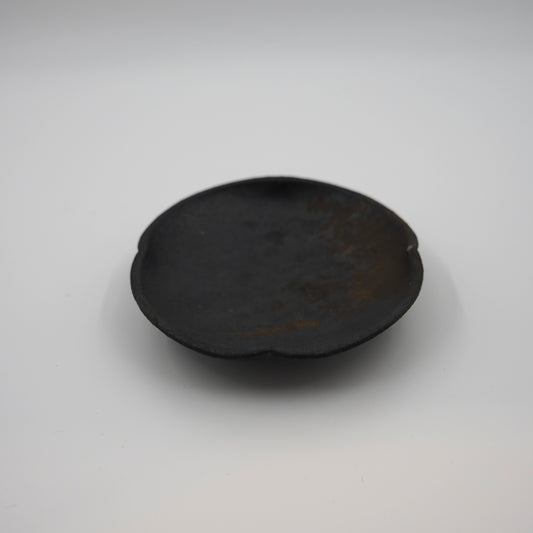 Black ceramic plate on a white background. Handmade ceramic  plate by Japanese artist at Gallery tete Hong Kong.