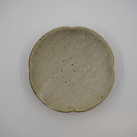 Round ceramic plate with a speckled glaze on a gray background
