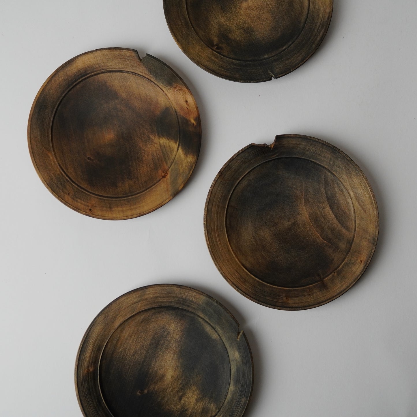 Four round, dark brown wooden coasters on a light gray background