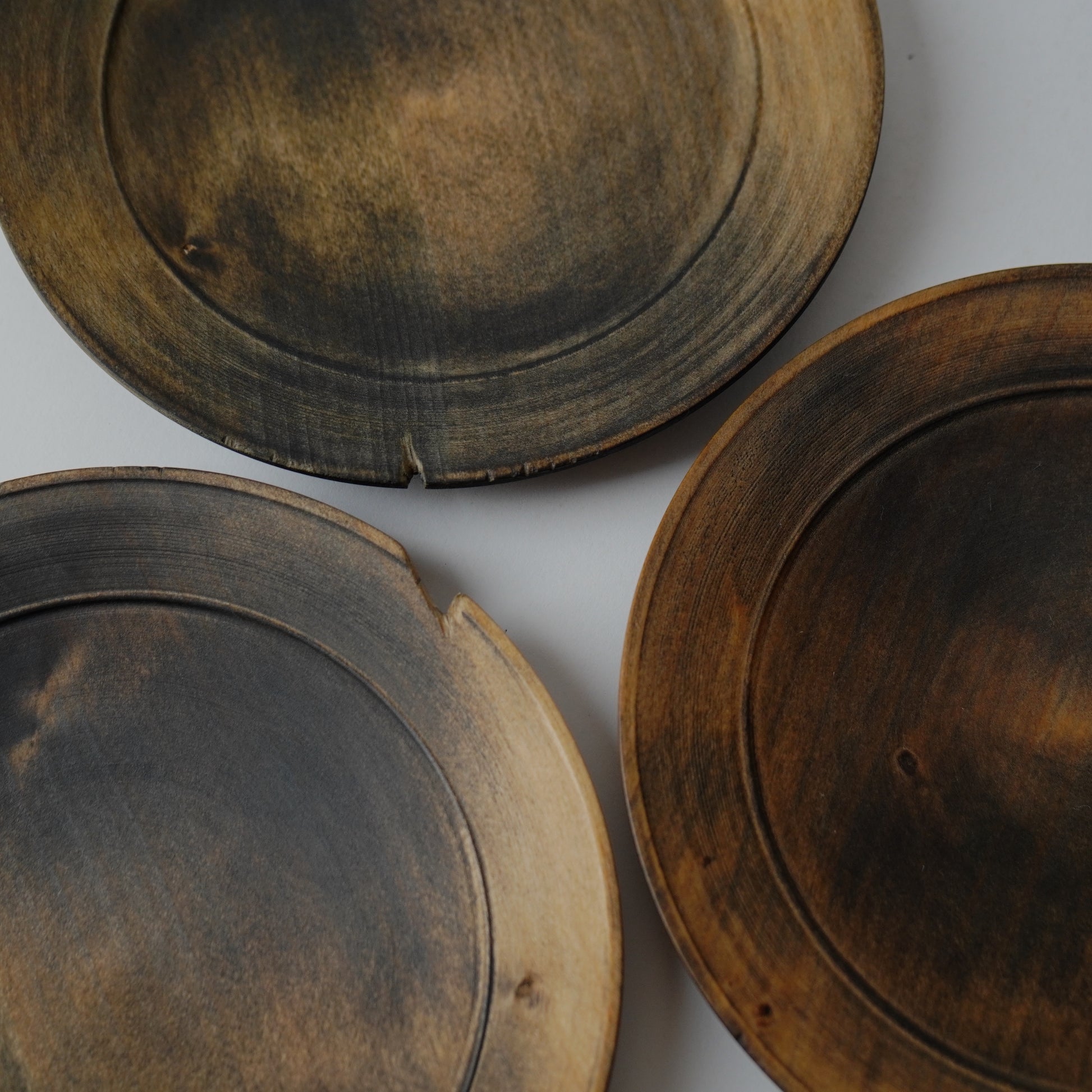 Three wooden plates with a rustic finish on a white background