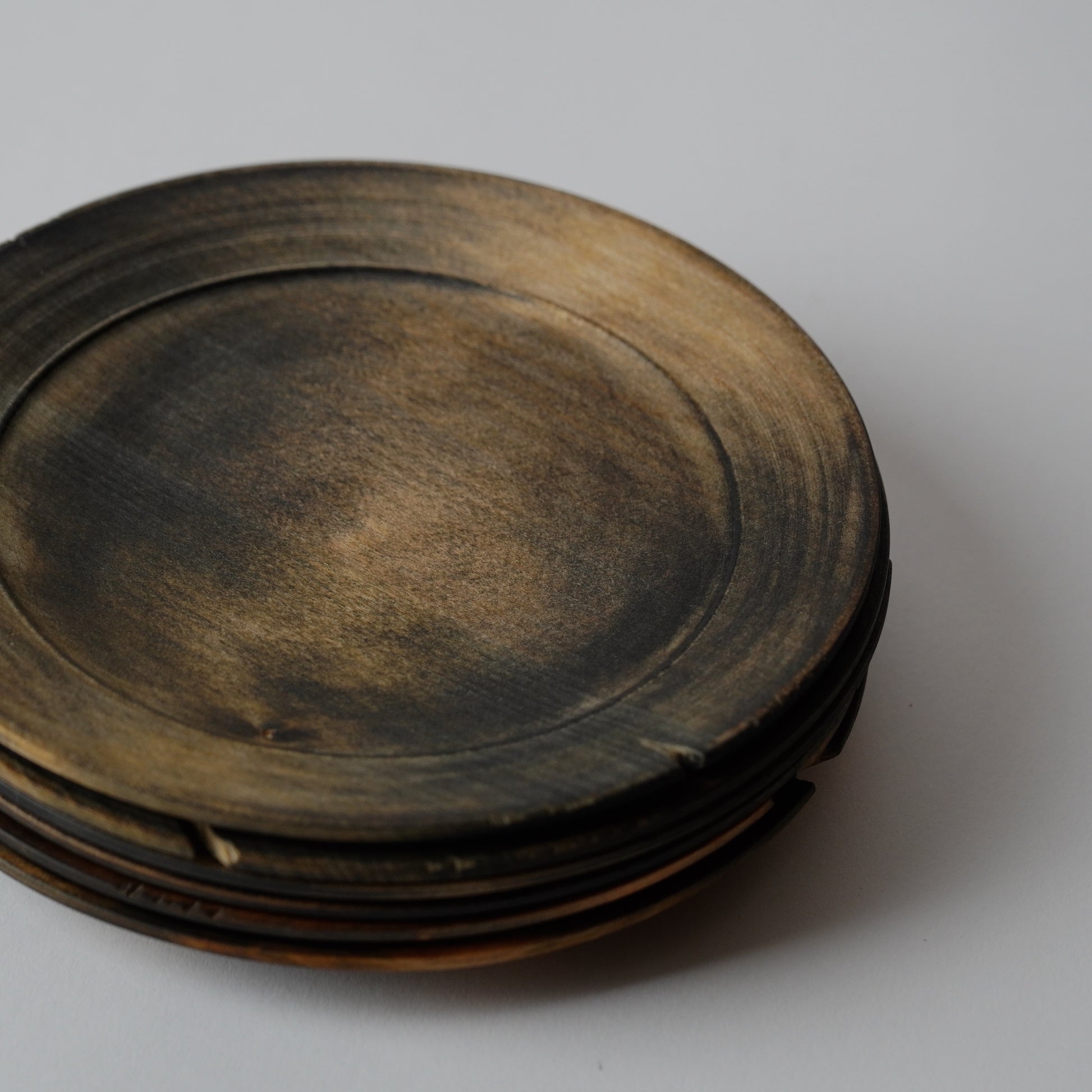 Stack of dark wooden plates on a light gray background