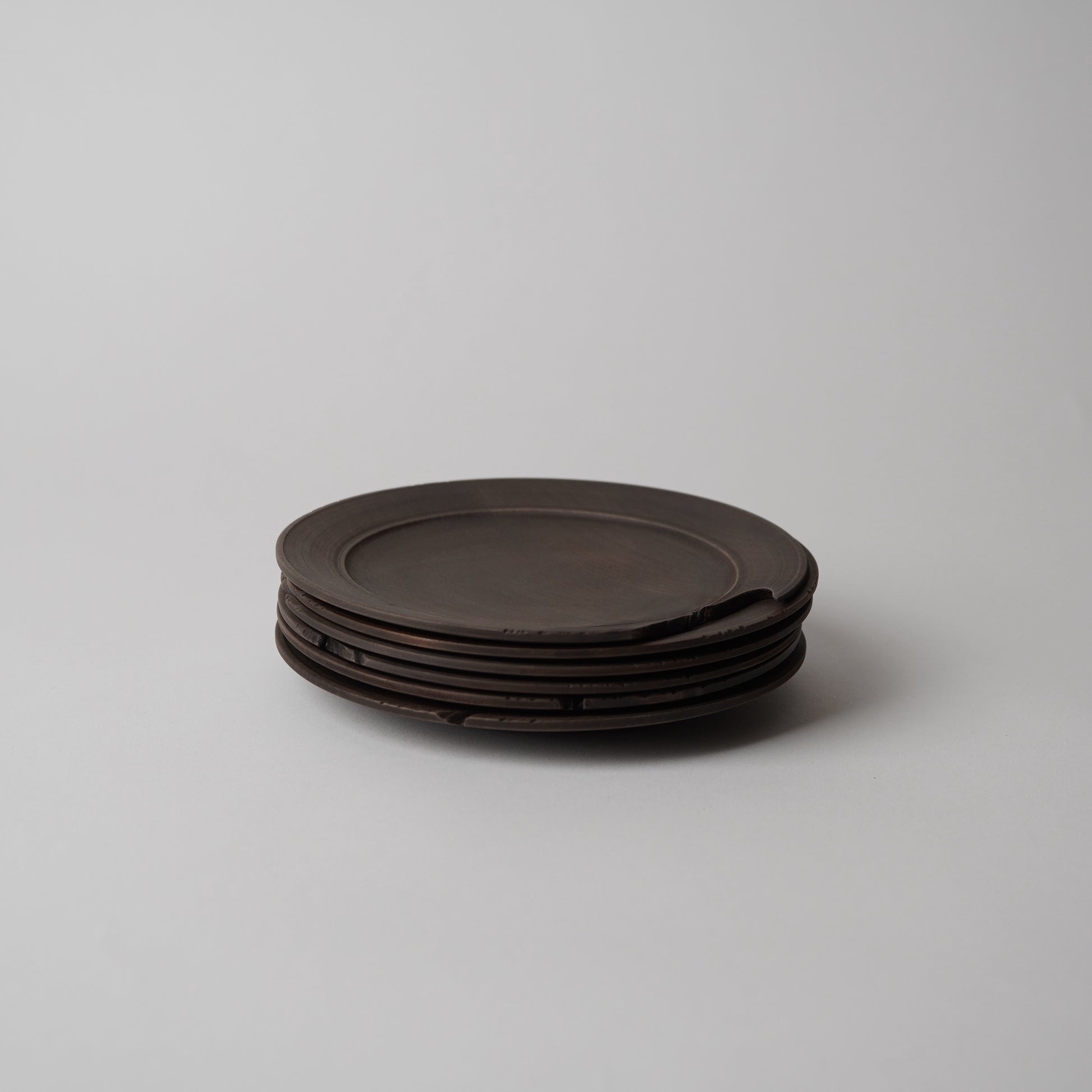 Stack of dark brown wooden plates on a light gray background