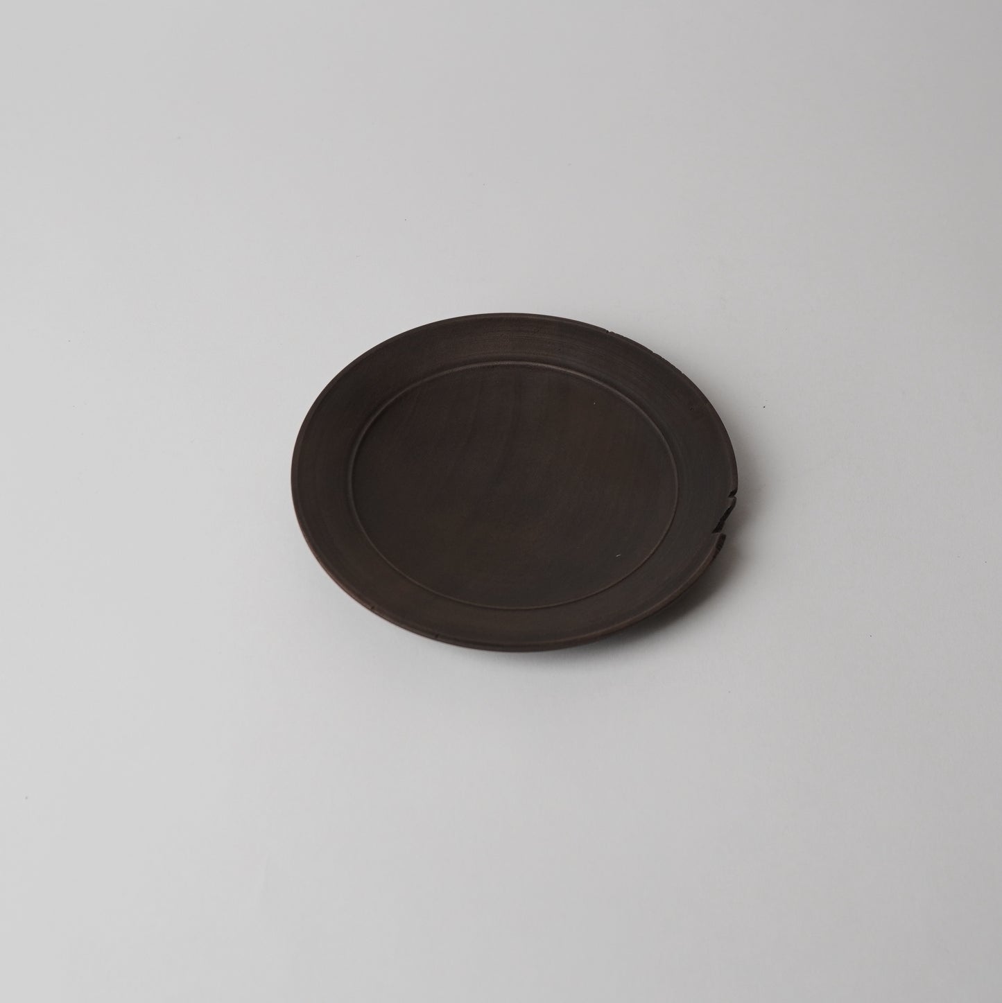 Round dark brown wooden plate on a light gray background