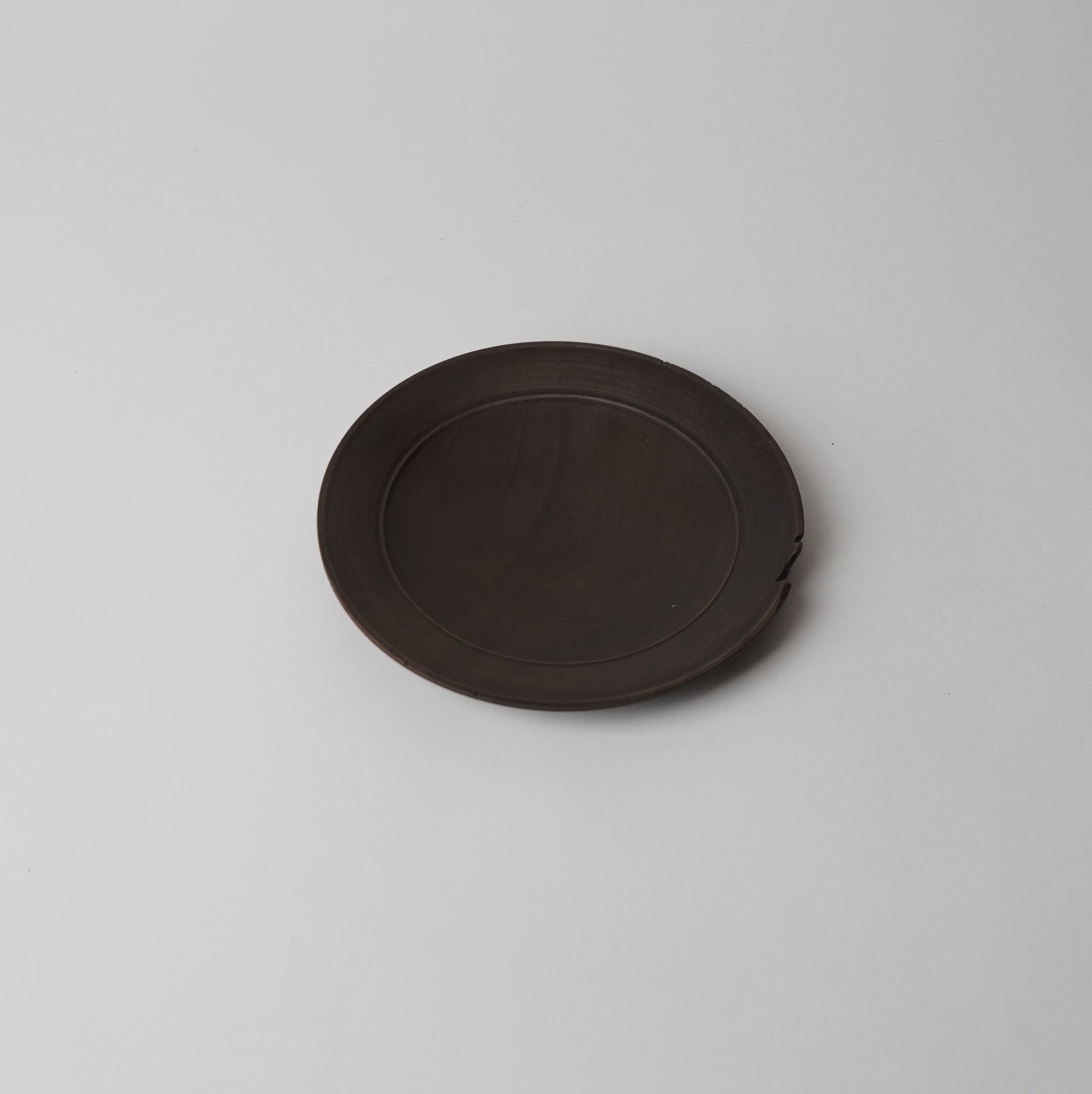 Round dark brown wooden plate on a light gray background