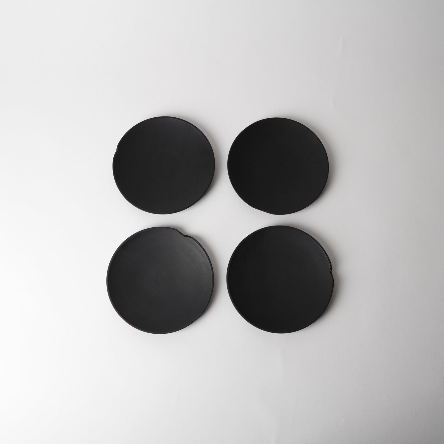Four black round  side plates on a light gray background