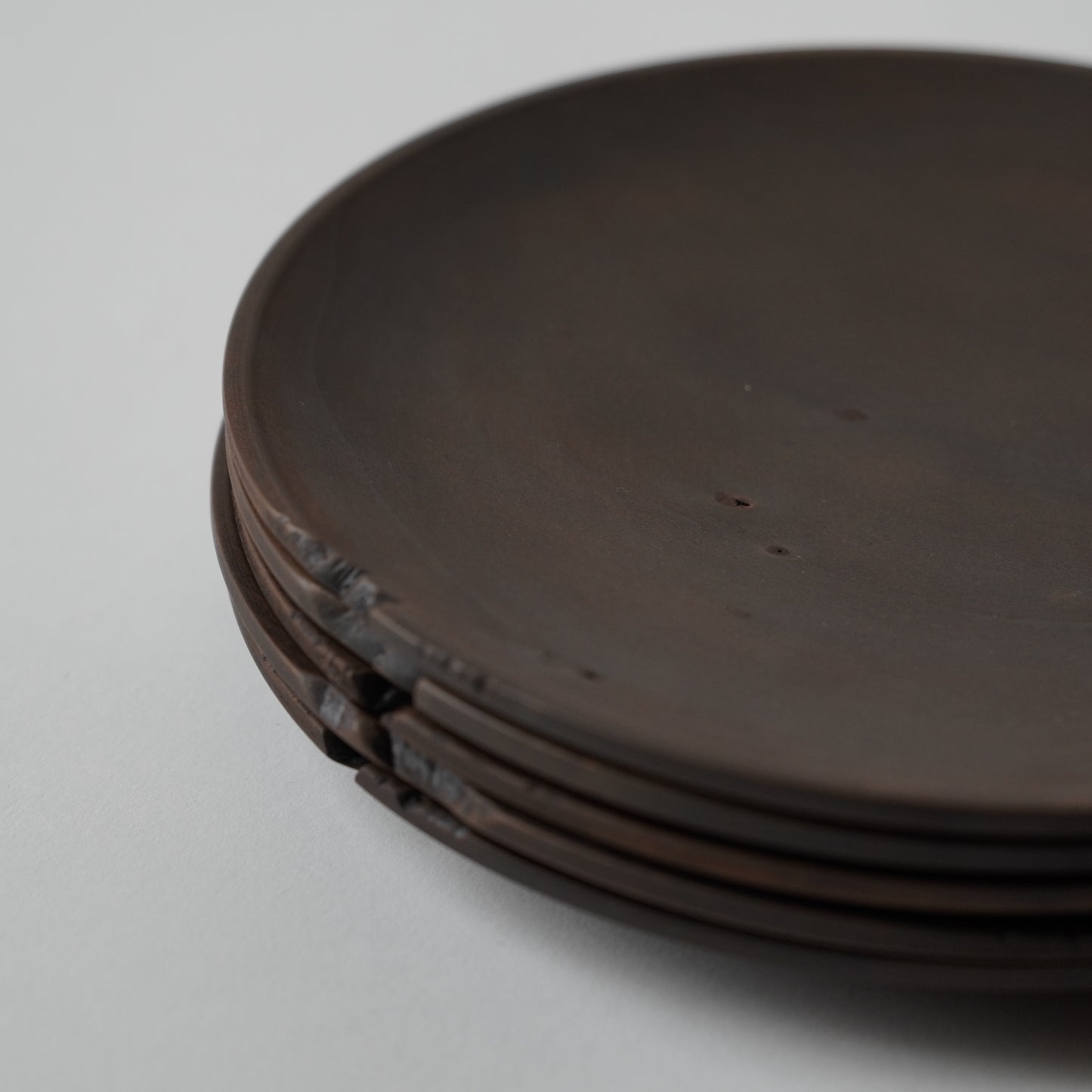 Stack of dark brown wooden plates on a light gray background 