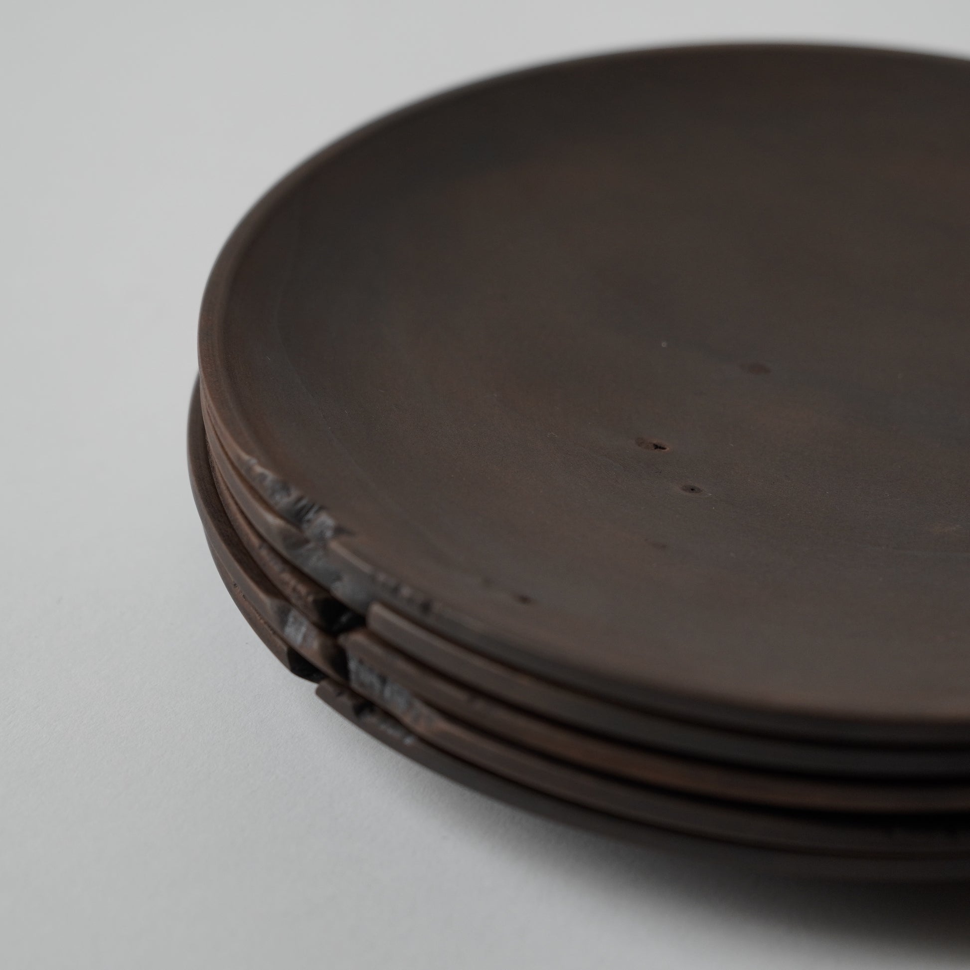 Stack of dark brown wooden plates on a light gray background 