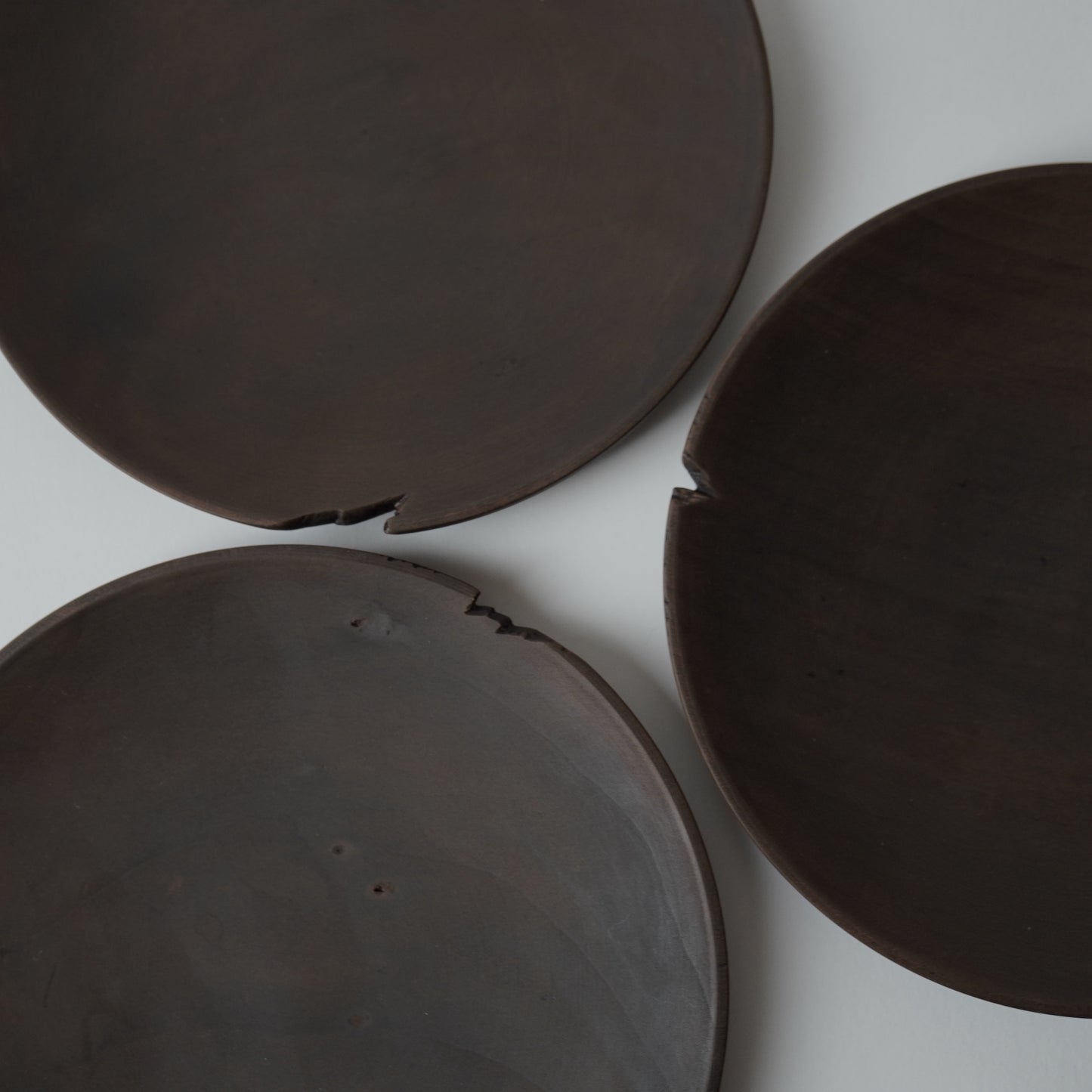 Three dark brown wooden plates on a white background
