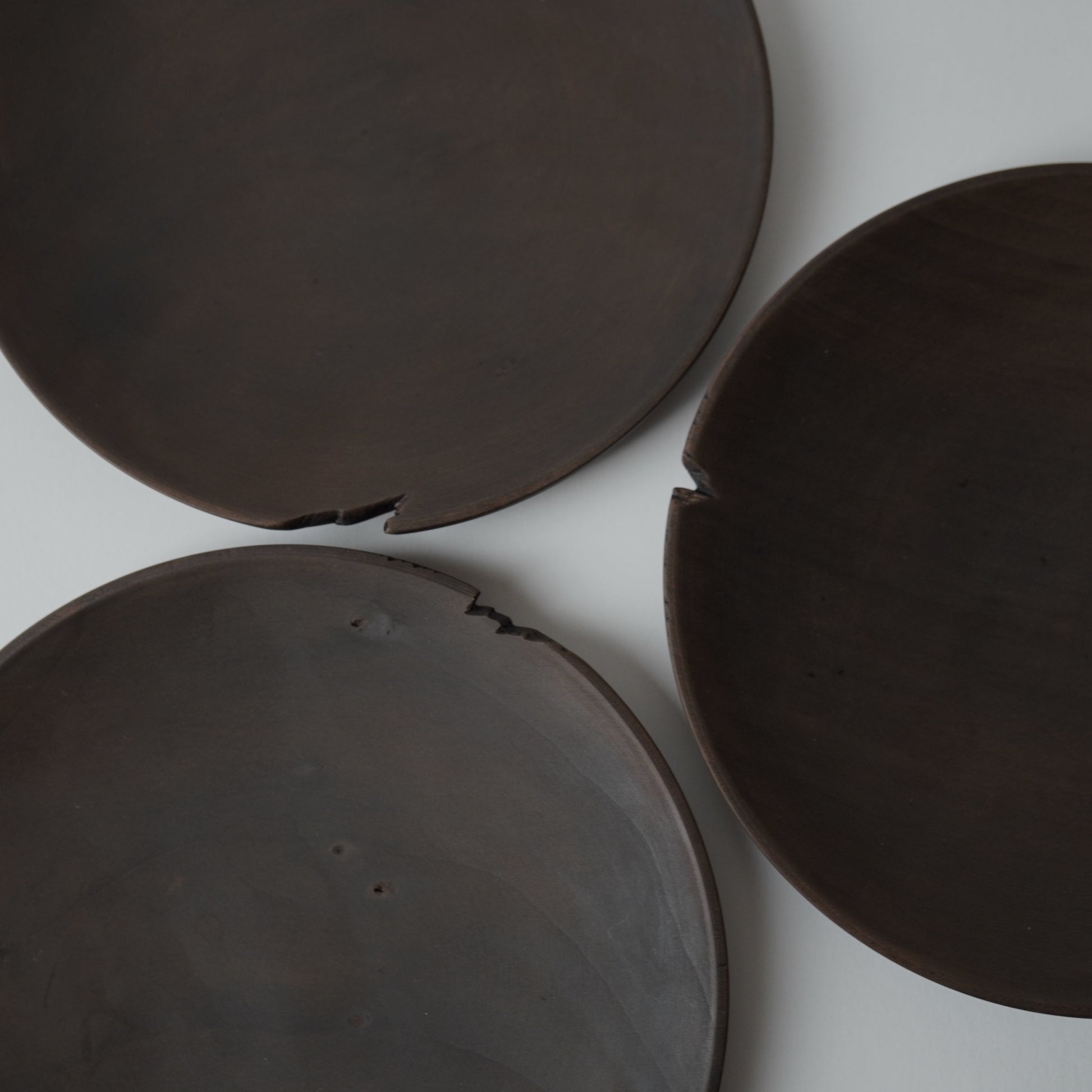 Three dark brown wooden plates on a white background