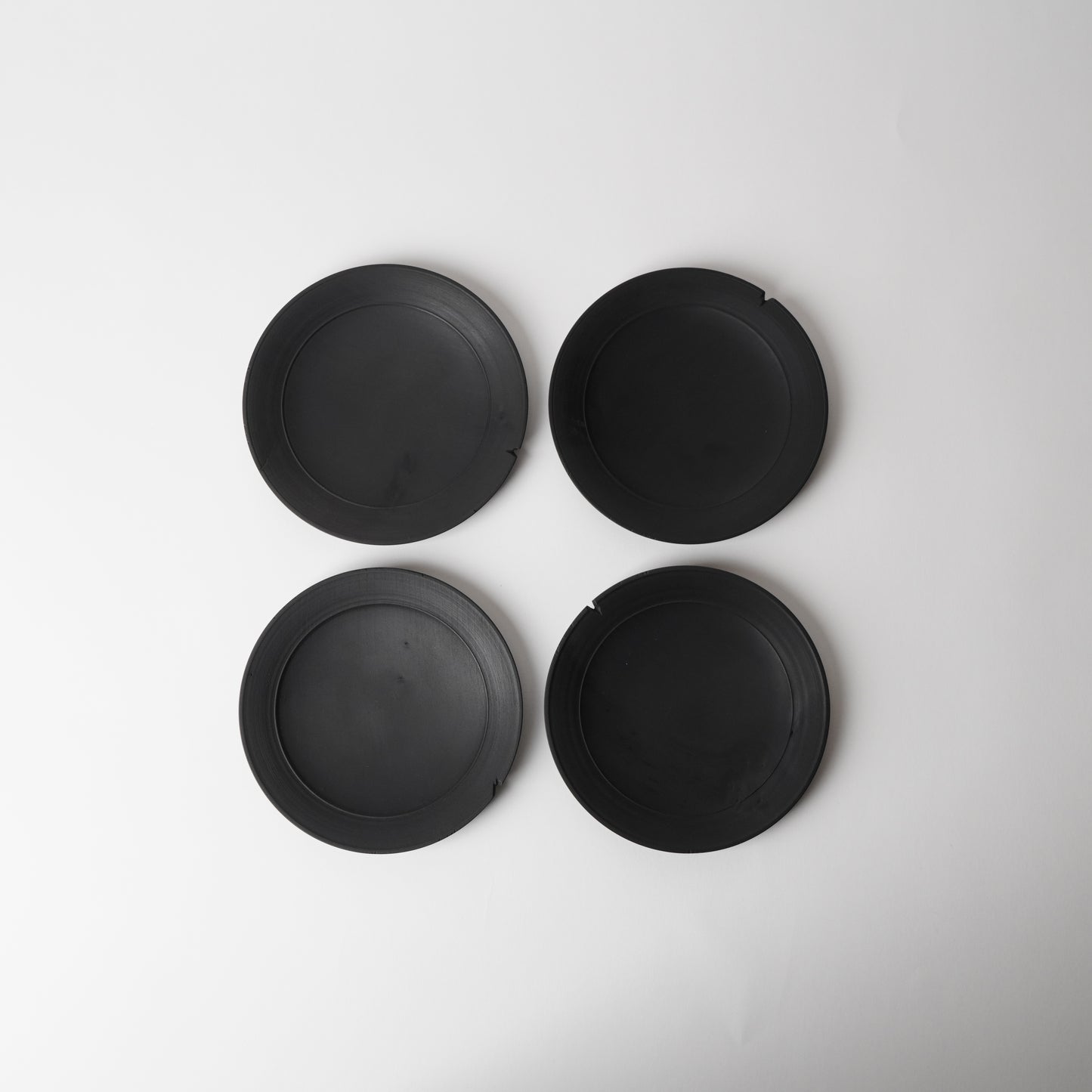 Four black wooden plates on a white background