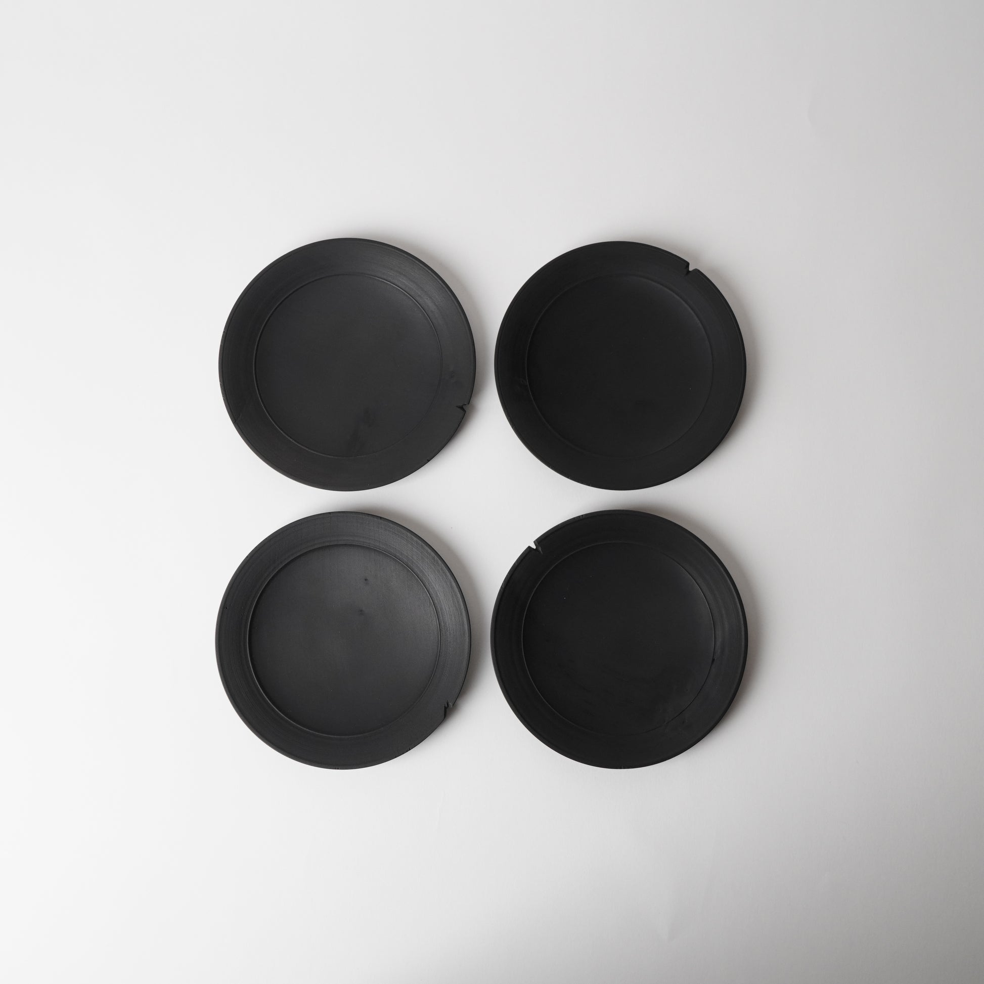Four black wooden plates on a white background