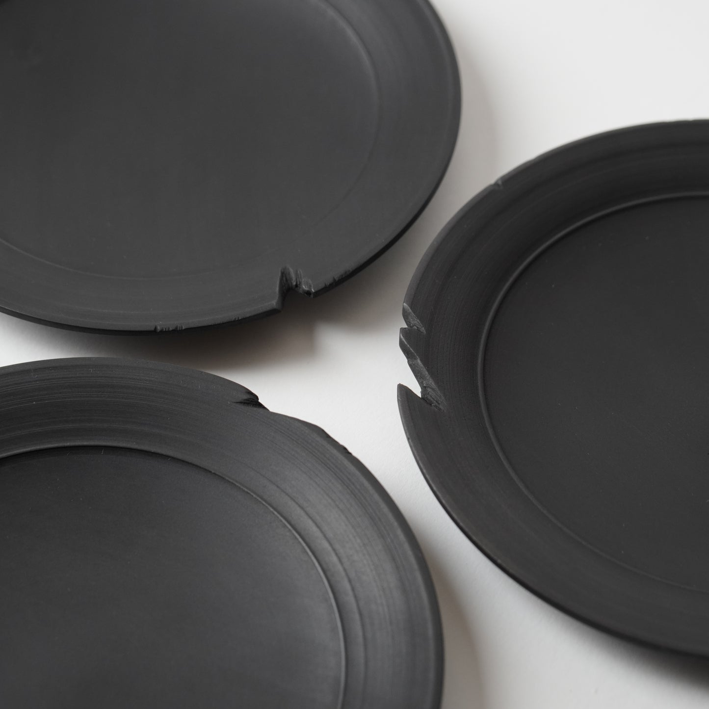 Three black wooden plates on a white background