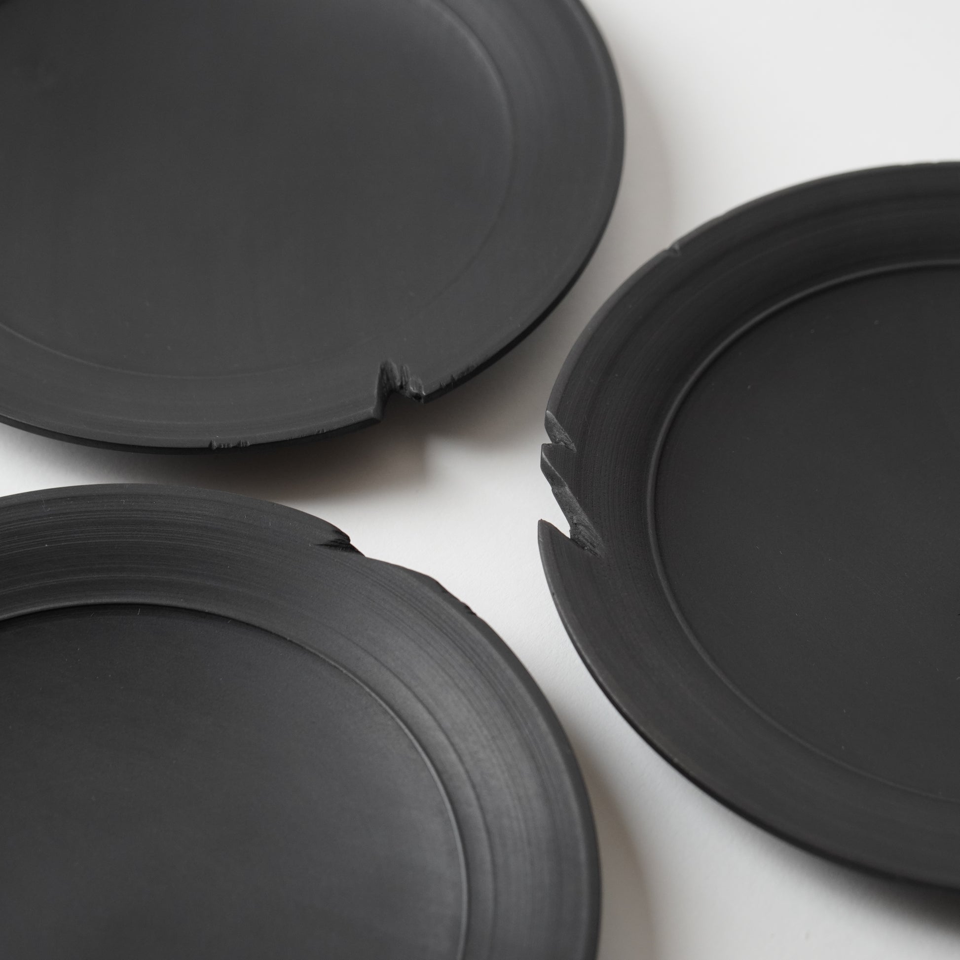 Three black wooden plates on a white background
