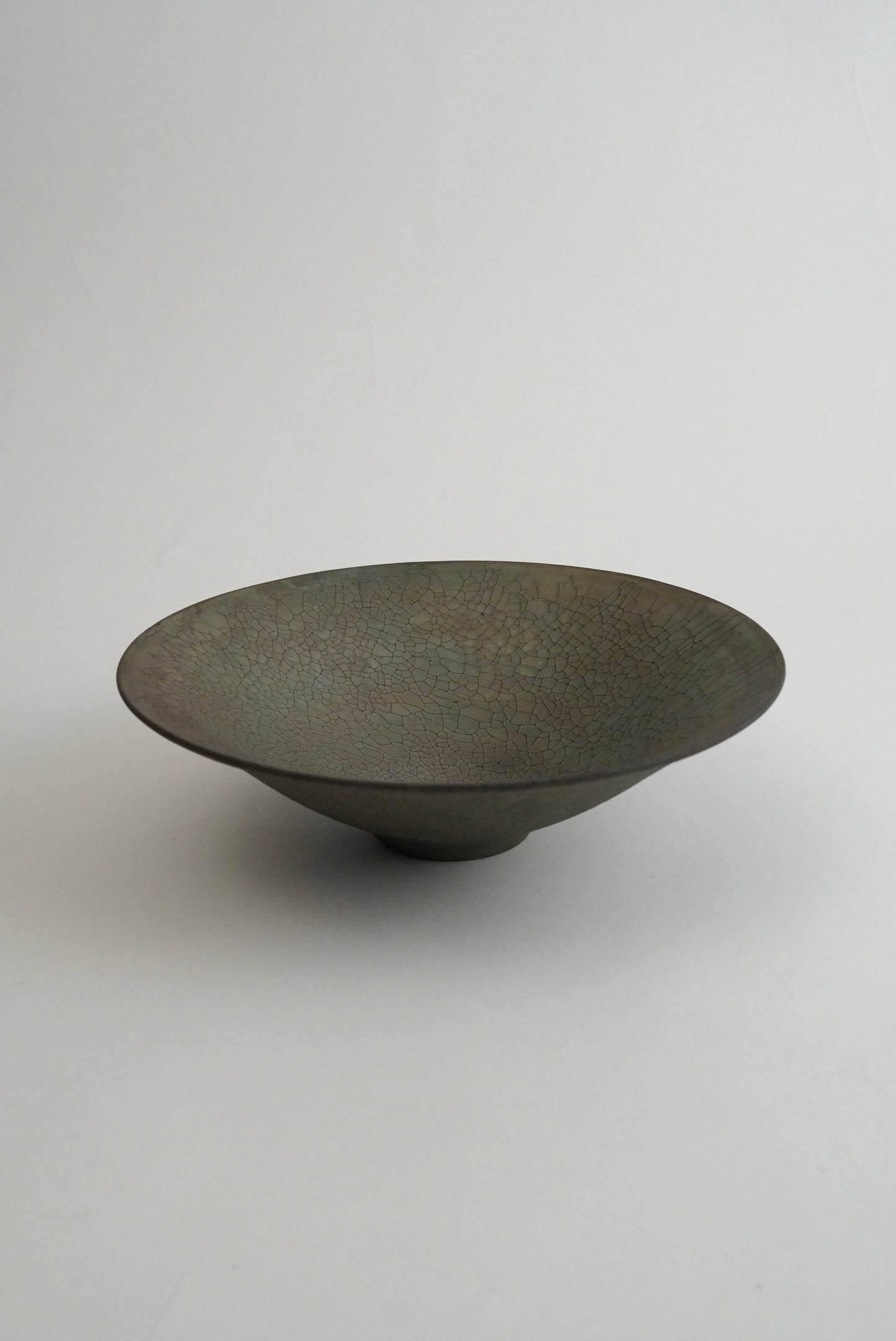 A dark gray ceramic bowl with a textured, speckled glaze, photographed on a neutral light gray background.