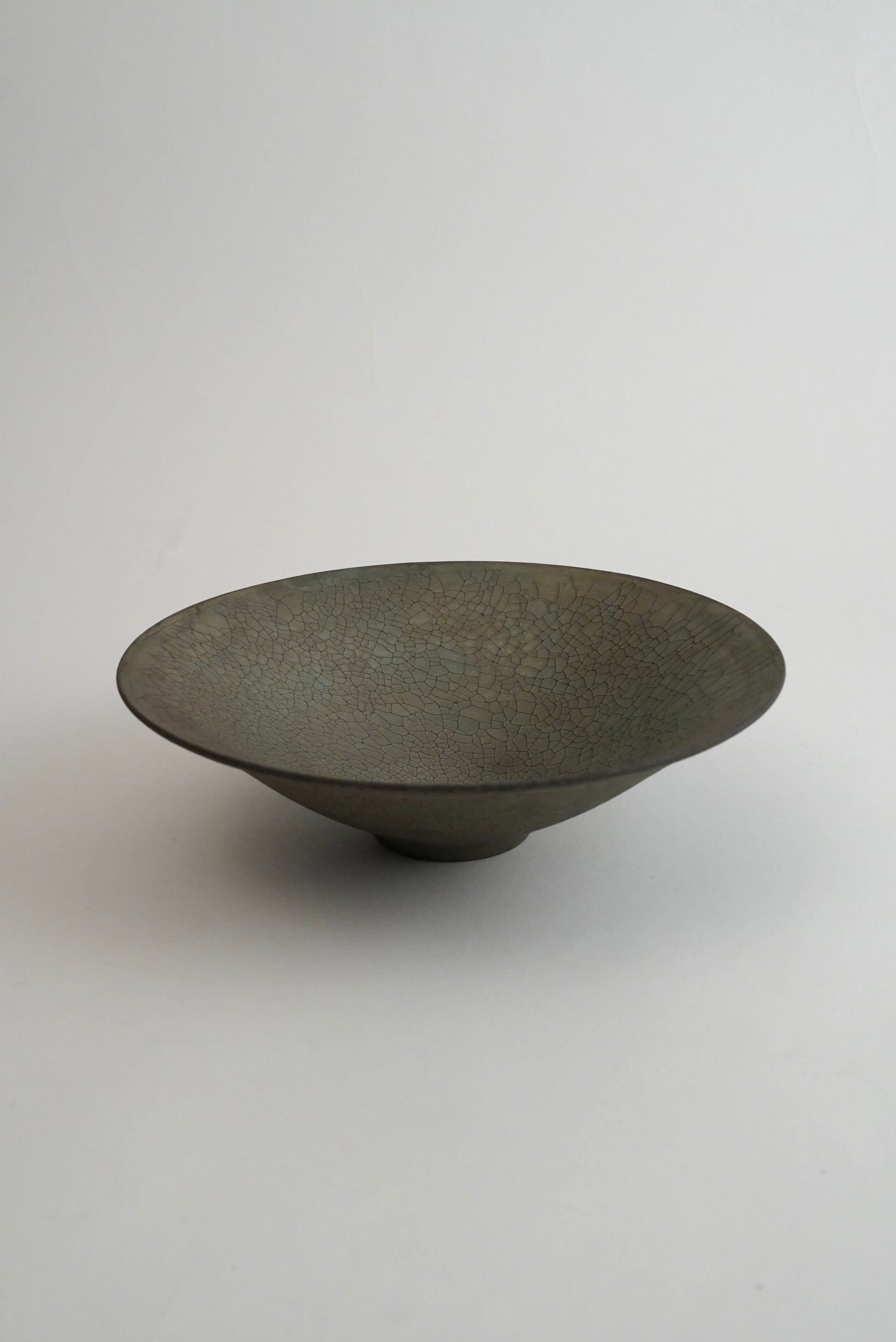 A dark gray ceramic bowl with a textured, speckled glaze, photographed on a neutral light gray background.