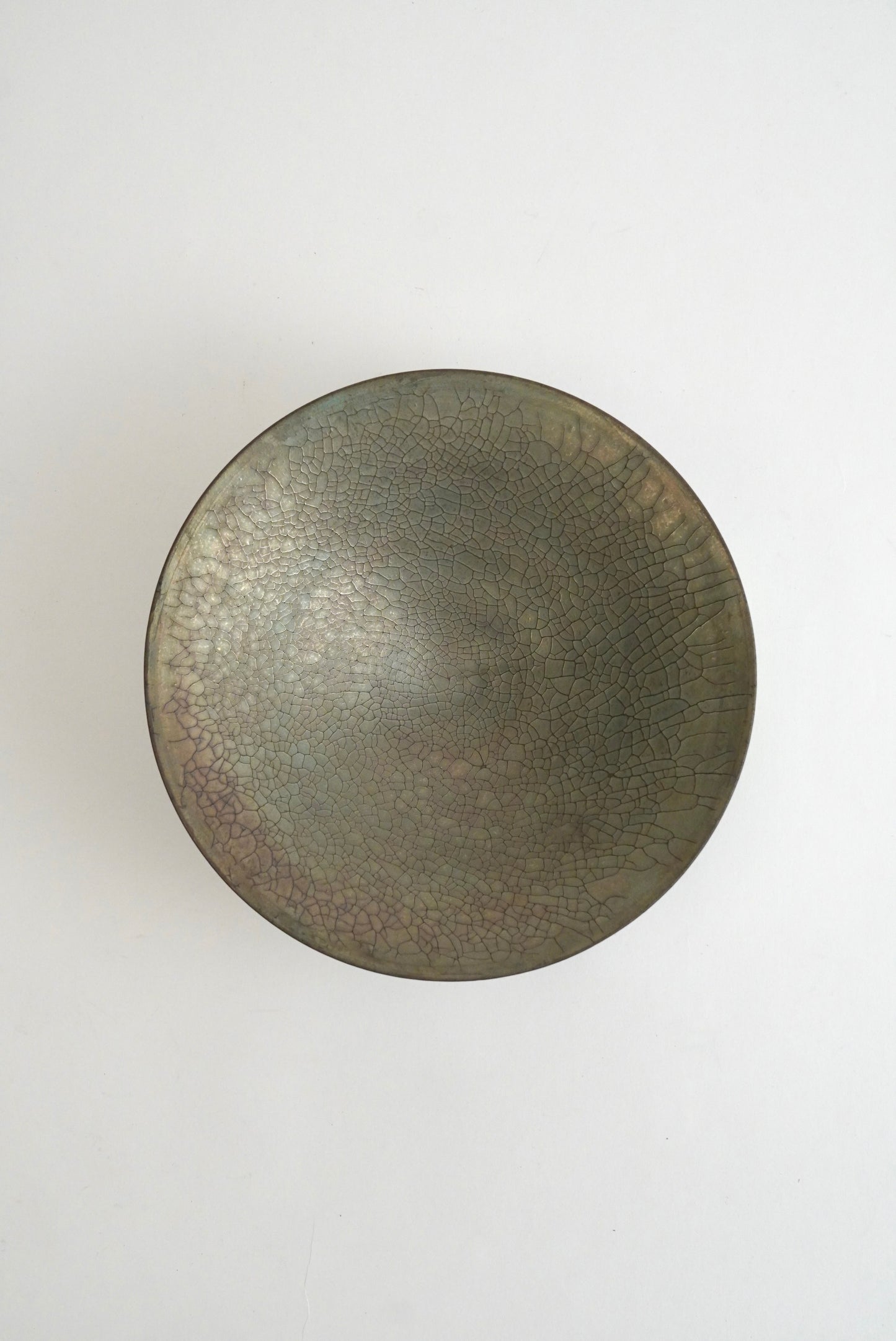A round ceramic bowl with a textured, crackled glaze in dark gray and brown tones, photographed from directly above on a clean white background.