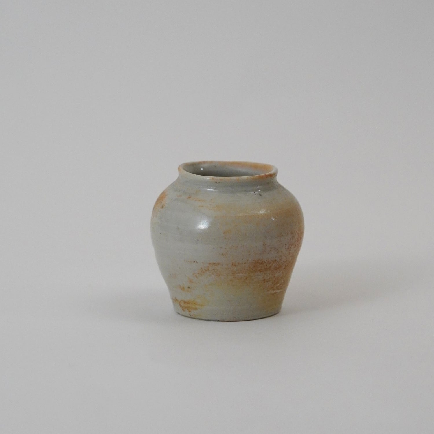 Small ceramic jar with a textured surface on a plain background