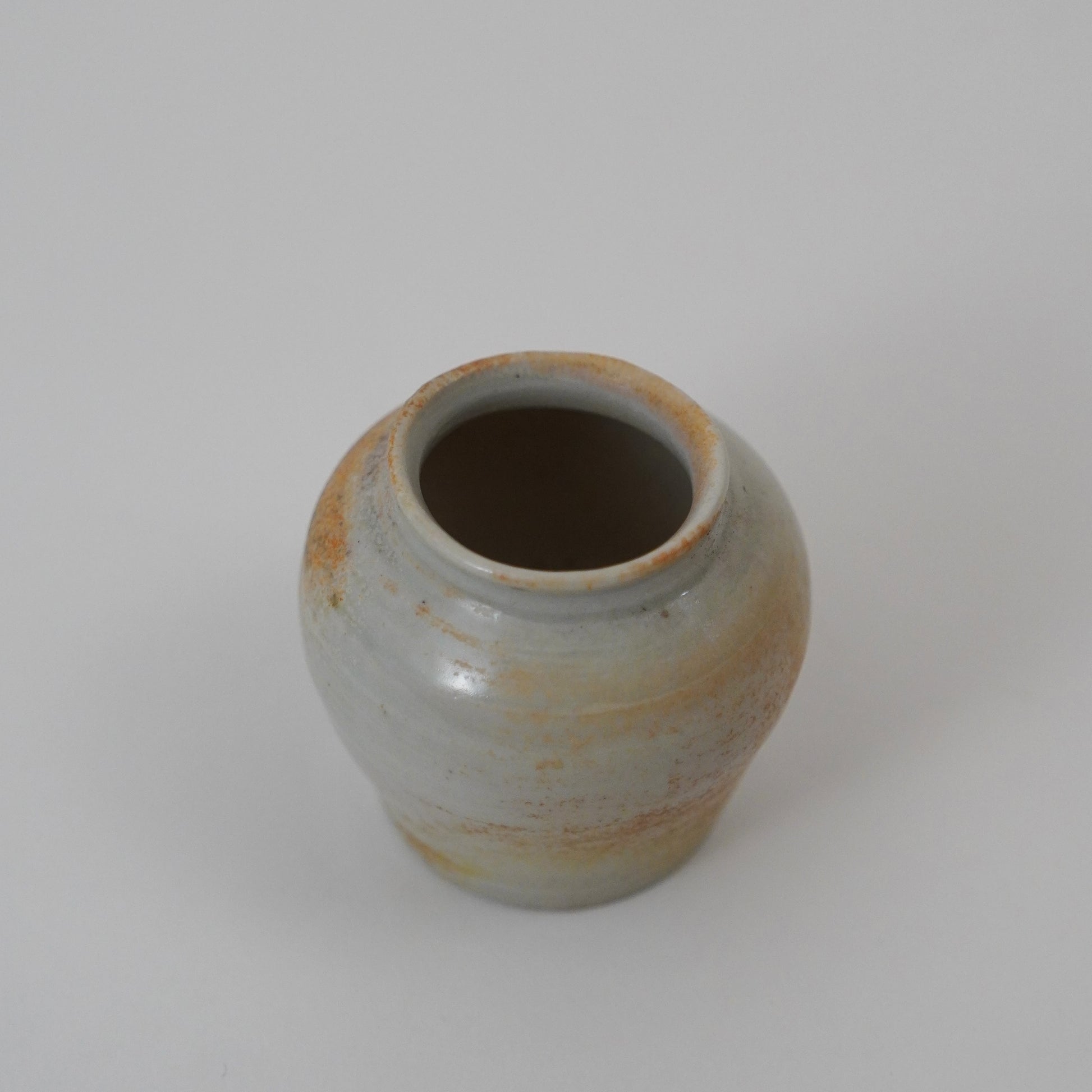 Small ceramic jar with a textured surface on a white background