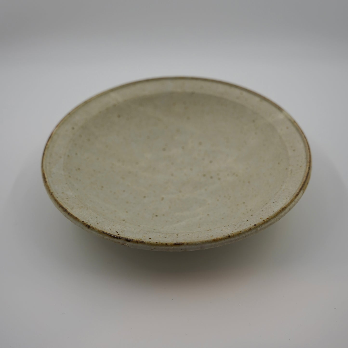 Ceramic plate with a speckled glaze on a white background