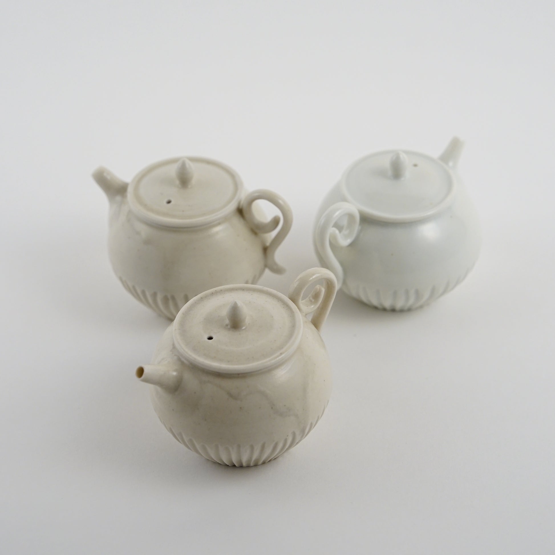 Three ceramic Chinese teapots made by Japanese Artist on a white background. Handmade porcelain chinese teapot by Japanese artist at Gallery tete Hong Kong.
