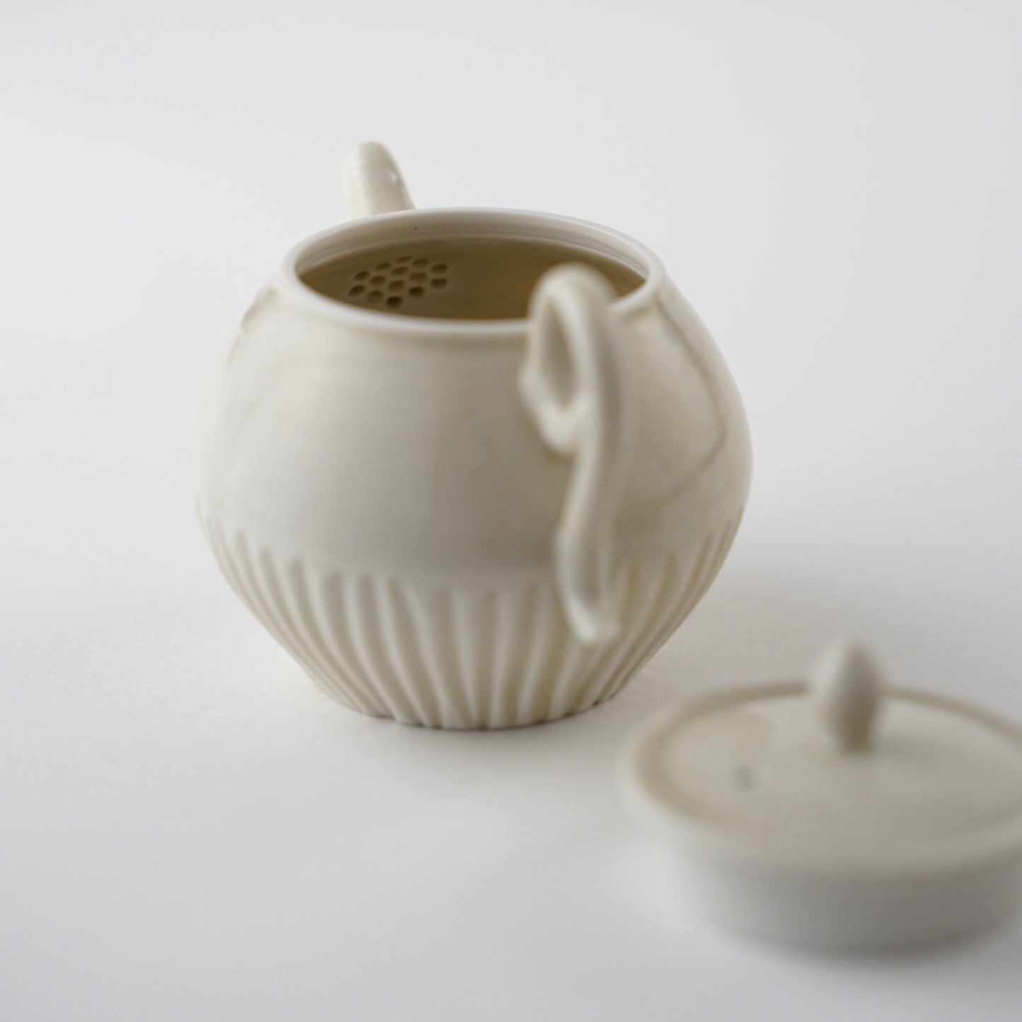 White ceramic Chinese teapot made by Japanese artist with lid on a light gray background.Handmade porcelain chinese teapot by Japanese artist at Gallery tete Hong Kong.