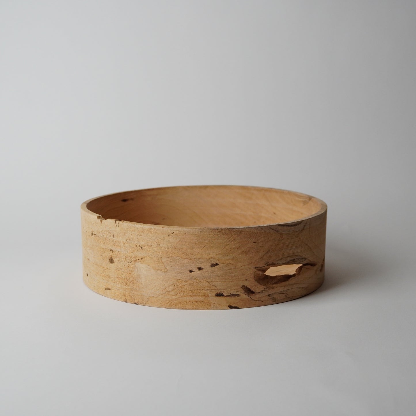 Wooden bowl with natural grain and texture on a light gray background