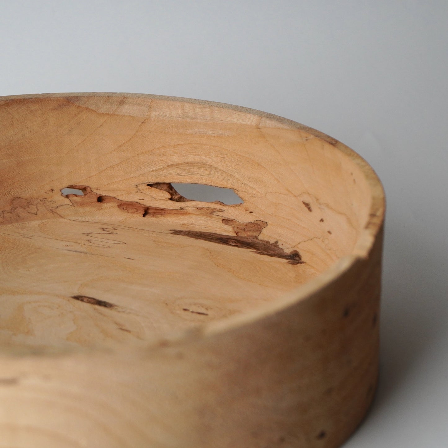 Close-up of a wooden bowl with natural grain and texture on a plain background