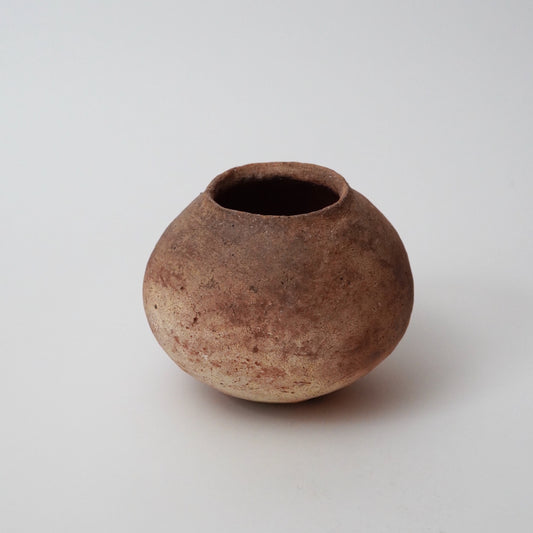 A brown ceramic vase with a round shape and a visible rim, placed against a white background.