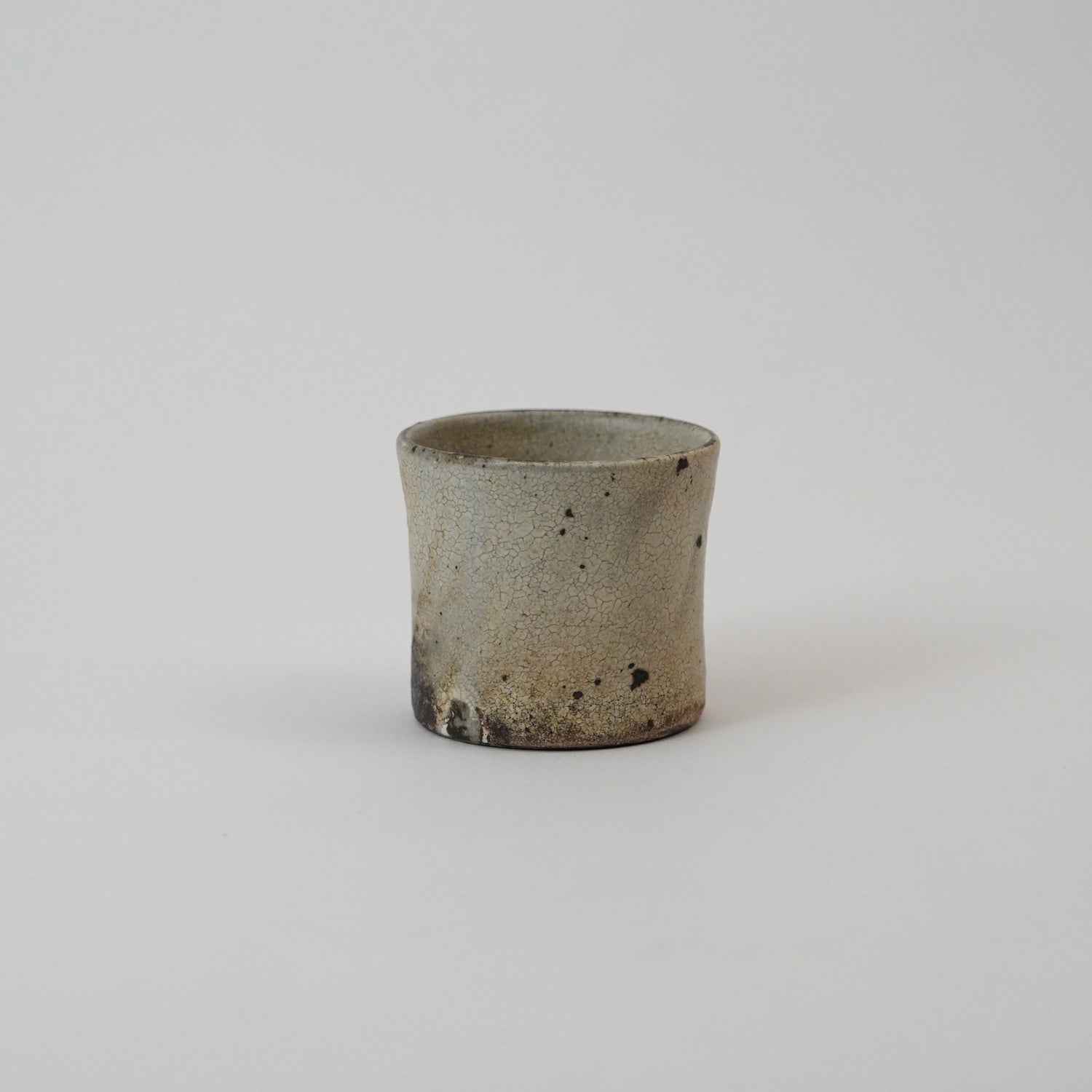 Small ceramic cup with a textured surface on a light gray background. Handmade ceramic cup by Japanese artist at Gallery tete Hong Kong.