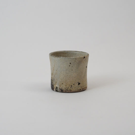 Small ceramic cup with a textured surface on a light gray background. Handmade ceramic cup by Japanese artist at Gallery tete Hong Kong.