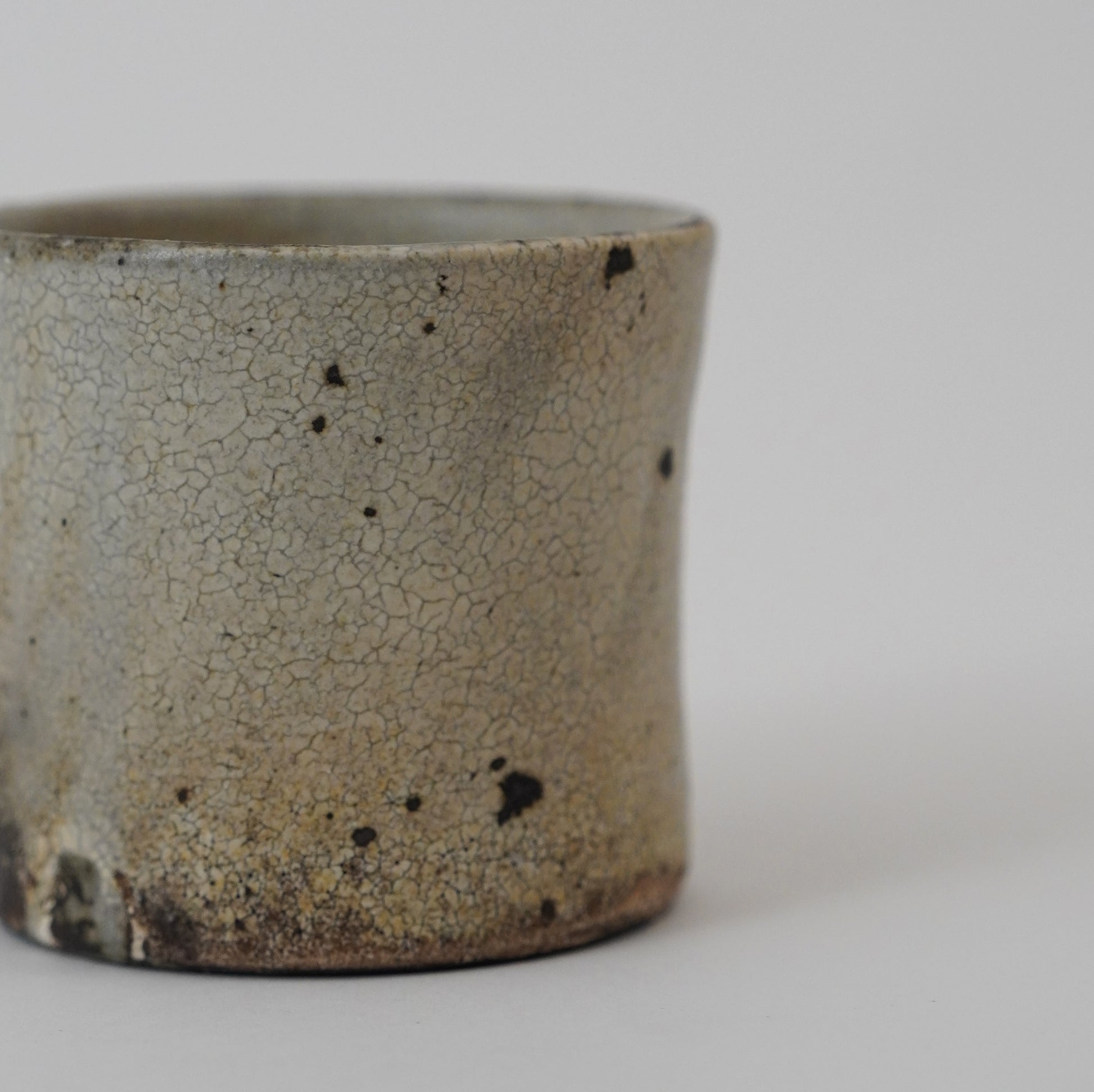 Ceramic cup with a textured surface on a plain background. Handmade ceramic cup by Japanese artist at Gallery tete Hong Kong.