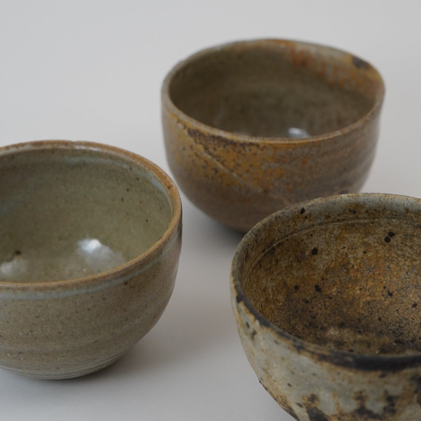 Three ceramic bowls with rustic glaze on a white background