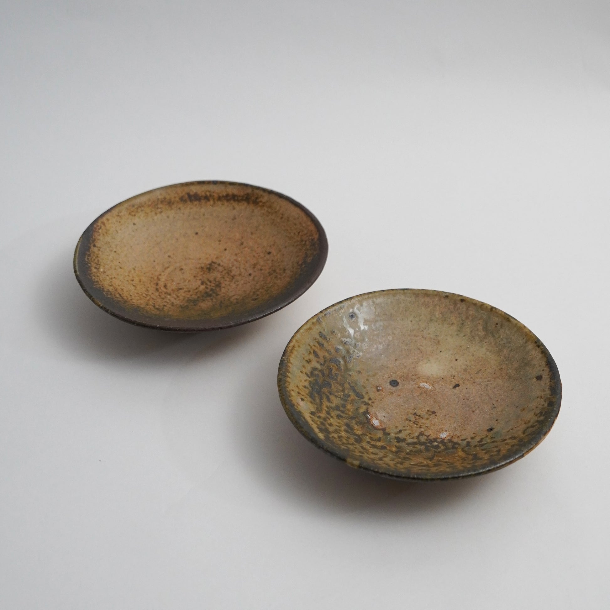 Two ceramic bowls with brown glaze on a white background. Handmade ceramic  plate by Japanese artist at Gallery tete Hong Kong.