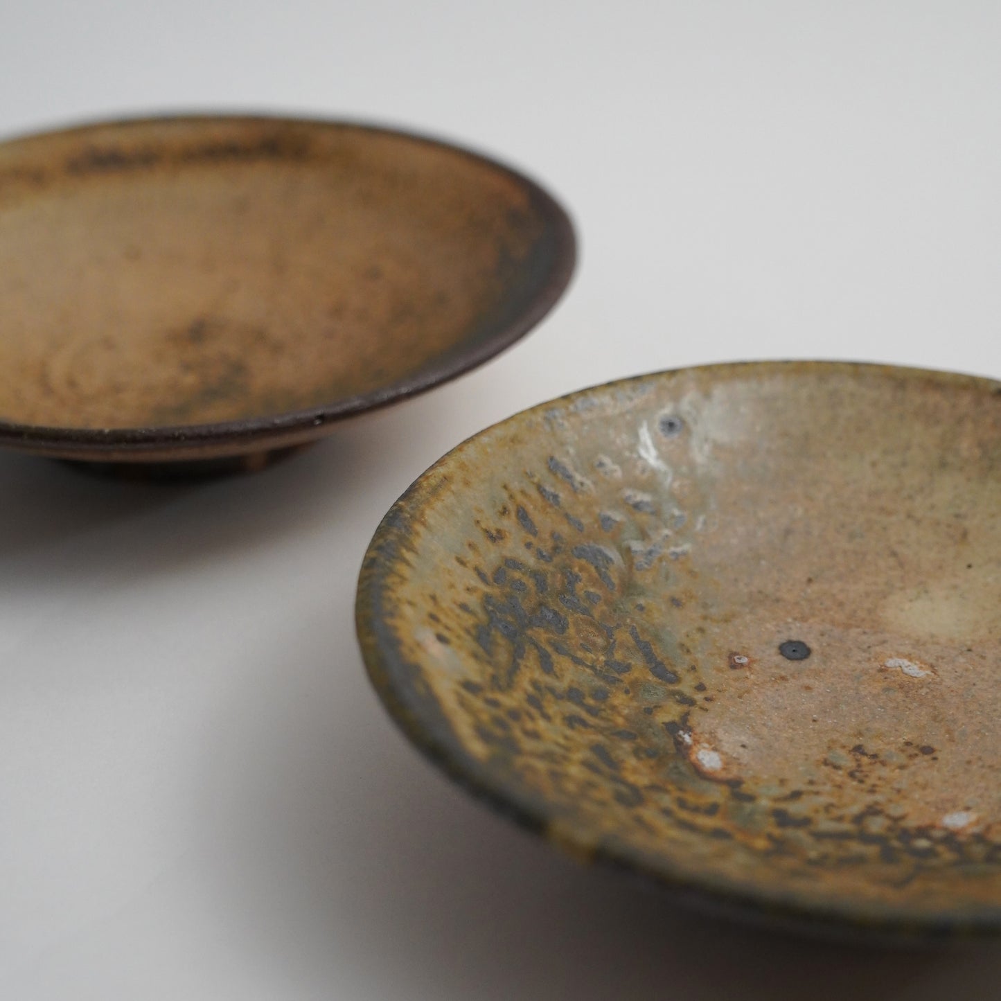 Two ceramic bowls with textured surfaces on a light background. Handmade ceramic  plate by Japanese artist at Gallery tete Hong Kong.
