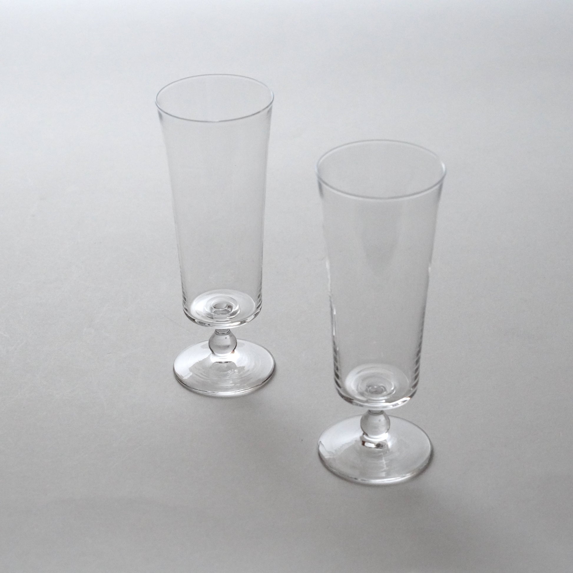 Two clear glass goblets on a light gray background. Handmade glass by Japanese artist at Gallery tete Hong Kong.