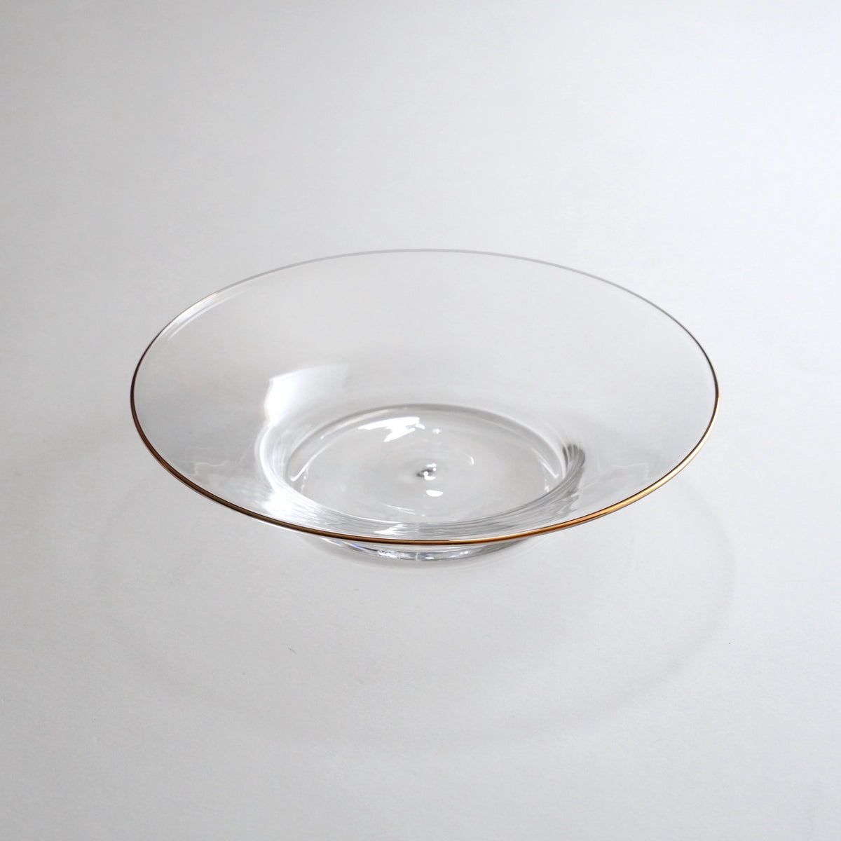 A clear glass plate with a gold rim on the edge, displayed against a neutral background.