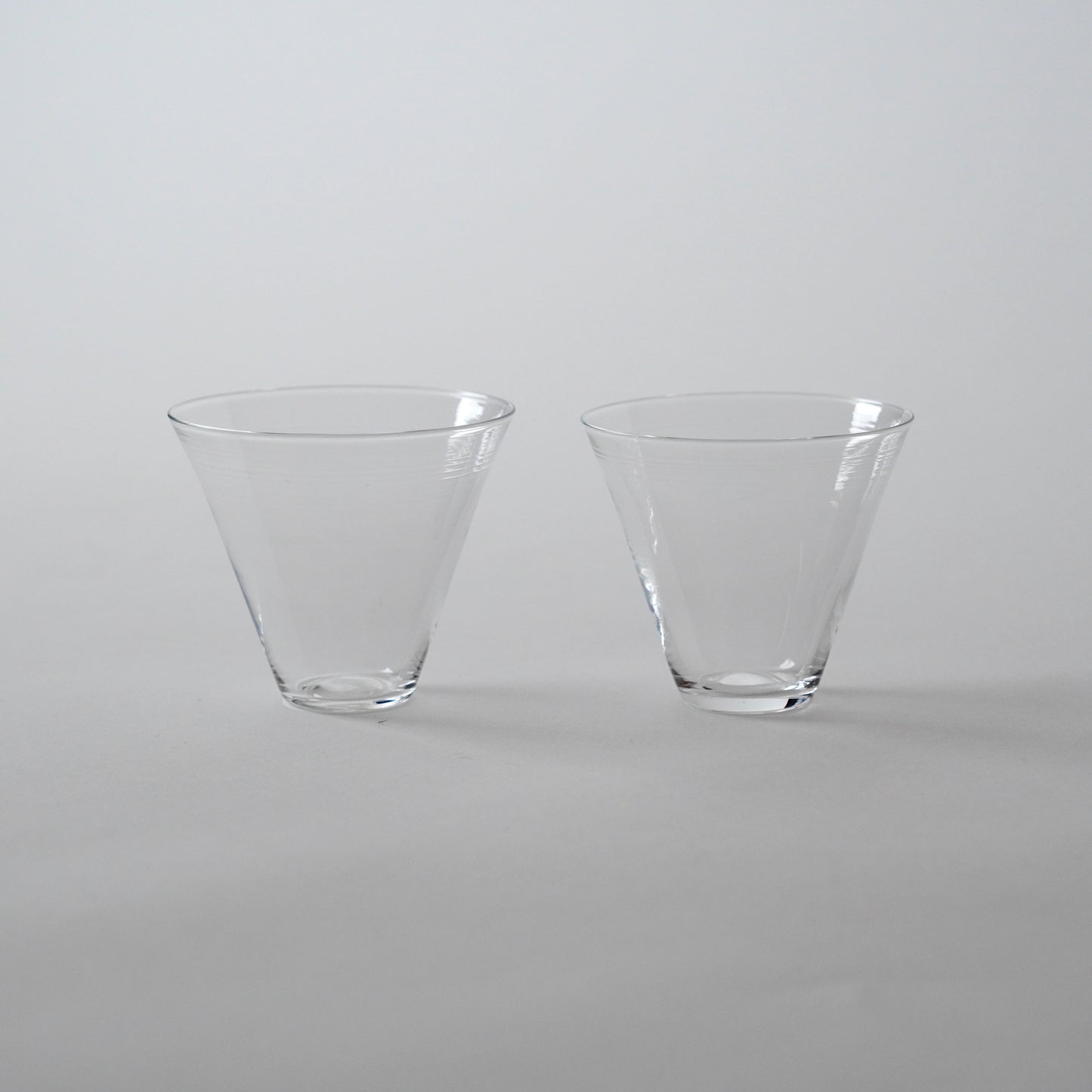 Two clear glass cold tea glasses placed side by side on a neutral background.