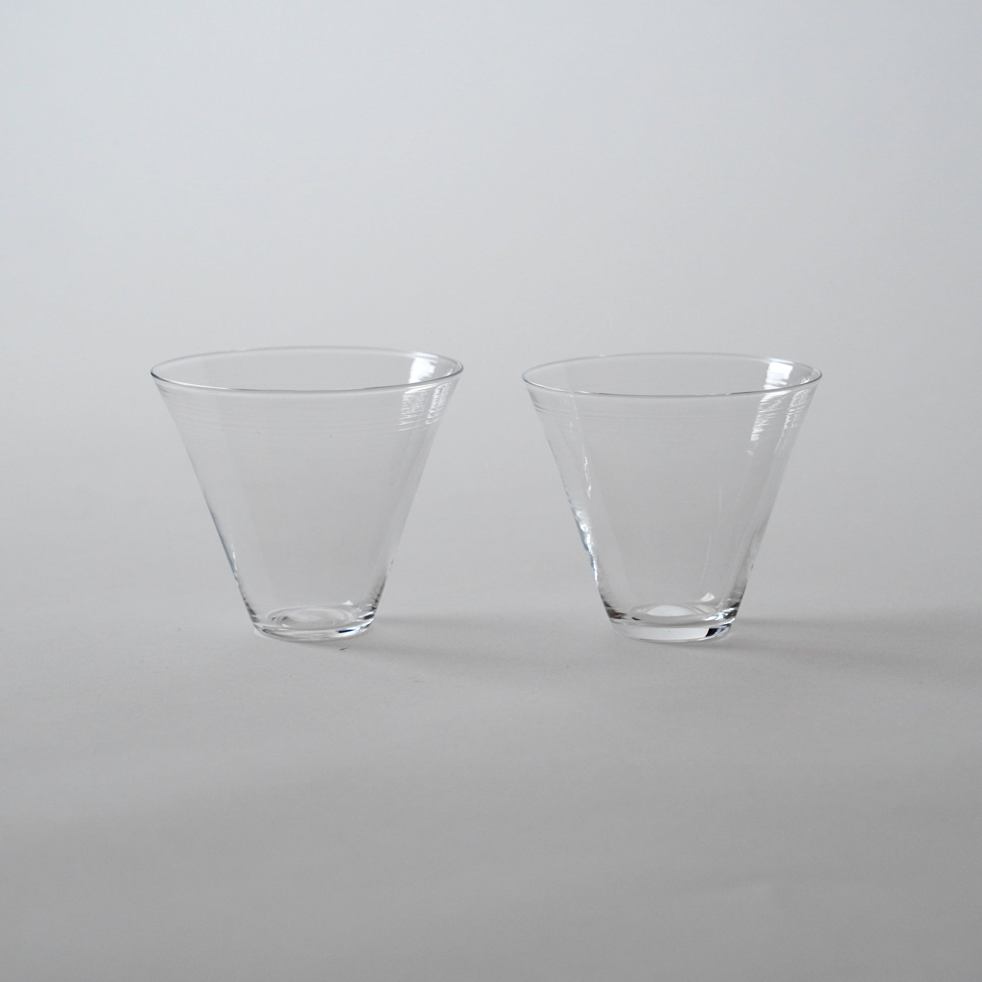 Two clear glass cold tea glasses placed side by side on a neutral background.