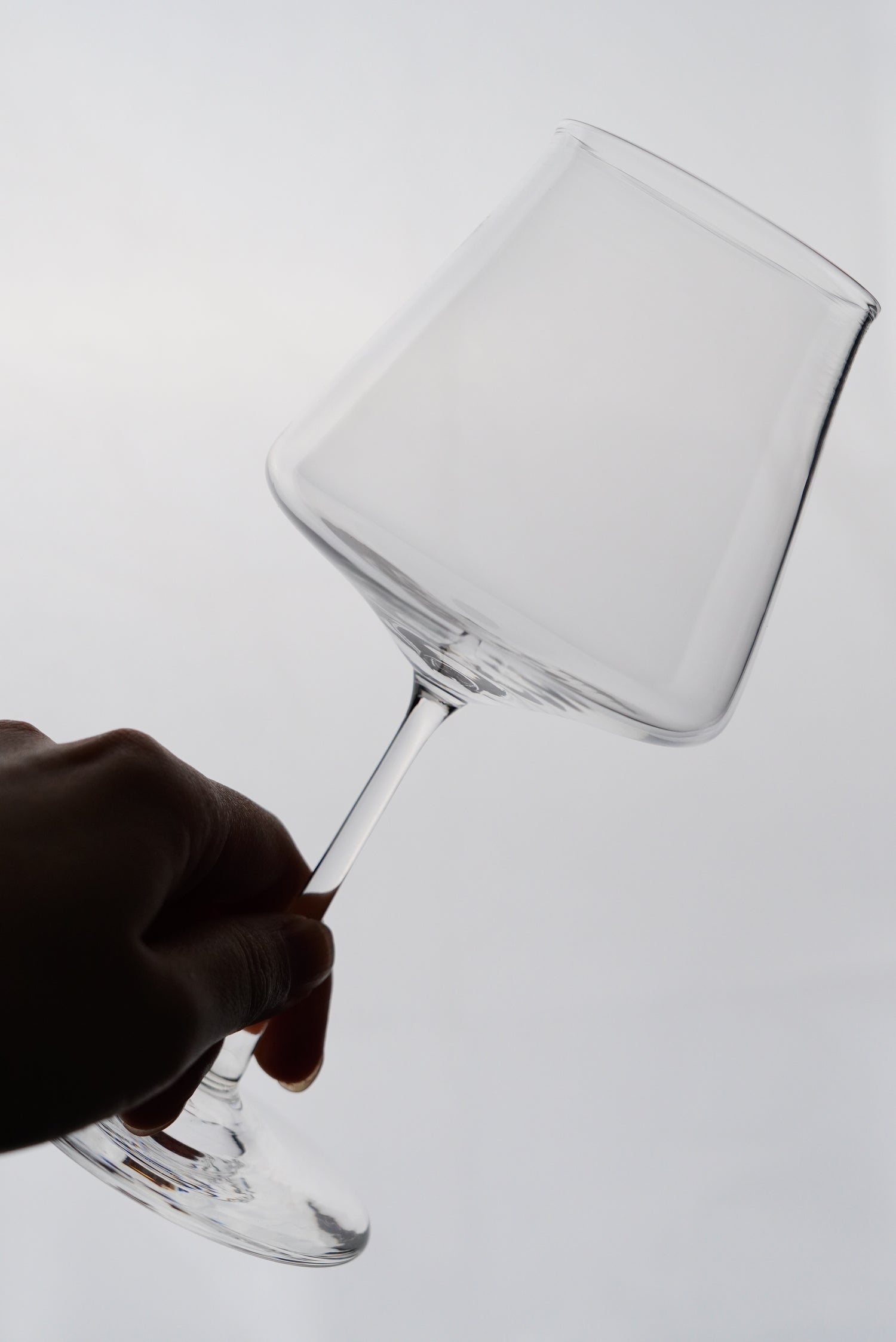 Hand holding a clear glass goblet against a white background